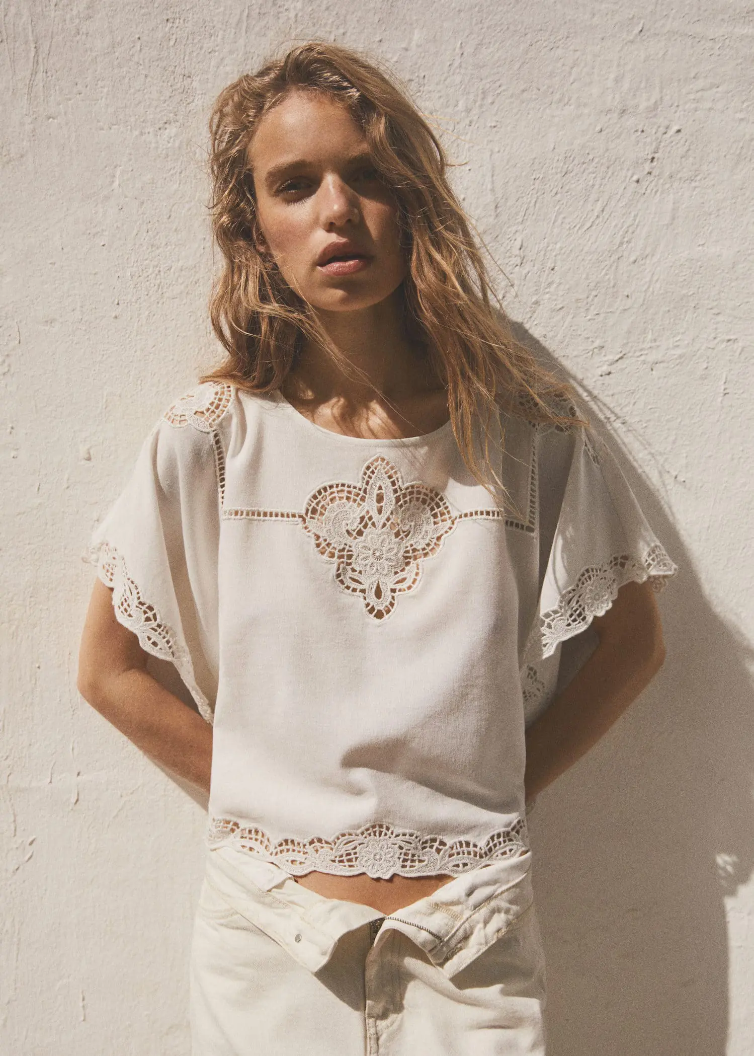 Mango Embroidered openwork blouse. a woman wearing a white top and white shorts. 