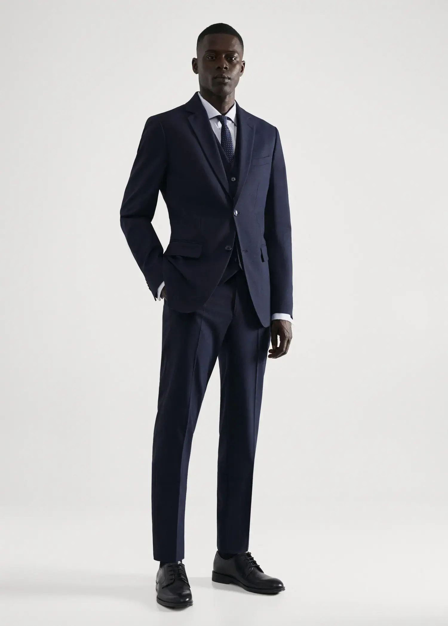 Mango Stretch fabric slim-fit suit pants. a man wearing a suit and tie standing in front of a white wall. 