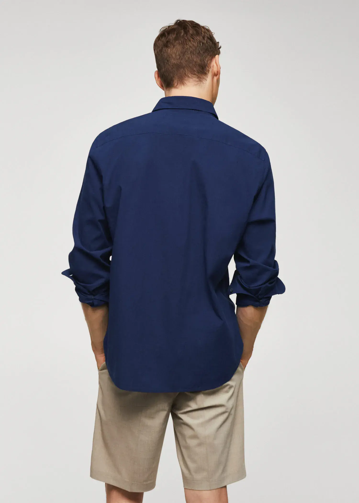 Mango Slim-fit cotton seersucker shirt. a man in a blue shirt is standing with his hands in his pockets 
