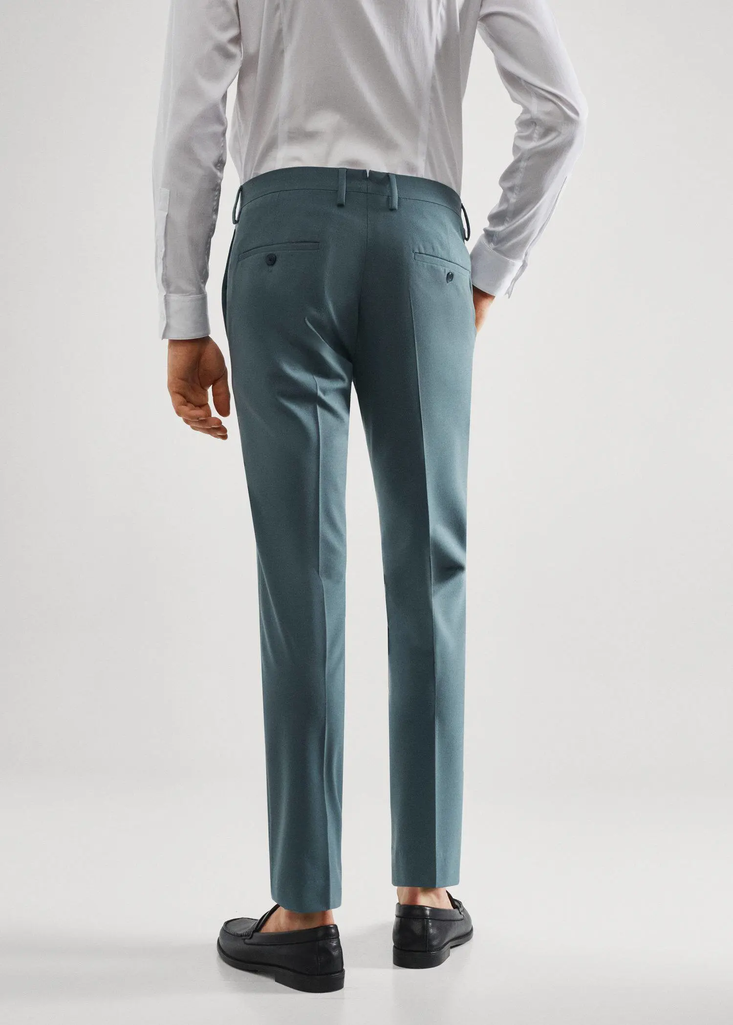 Mango Stretch fabric super slim-fit suit pants. a man wearing a suit standing in front of a white wall. 
