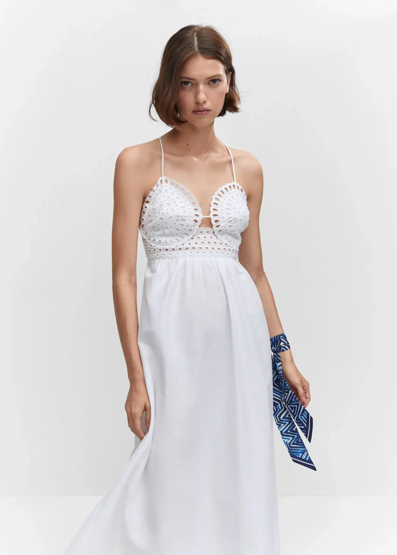 Mango Embroidered v-neckline dress. a woman in a white dress holding a blue bag. 