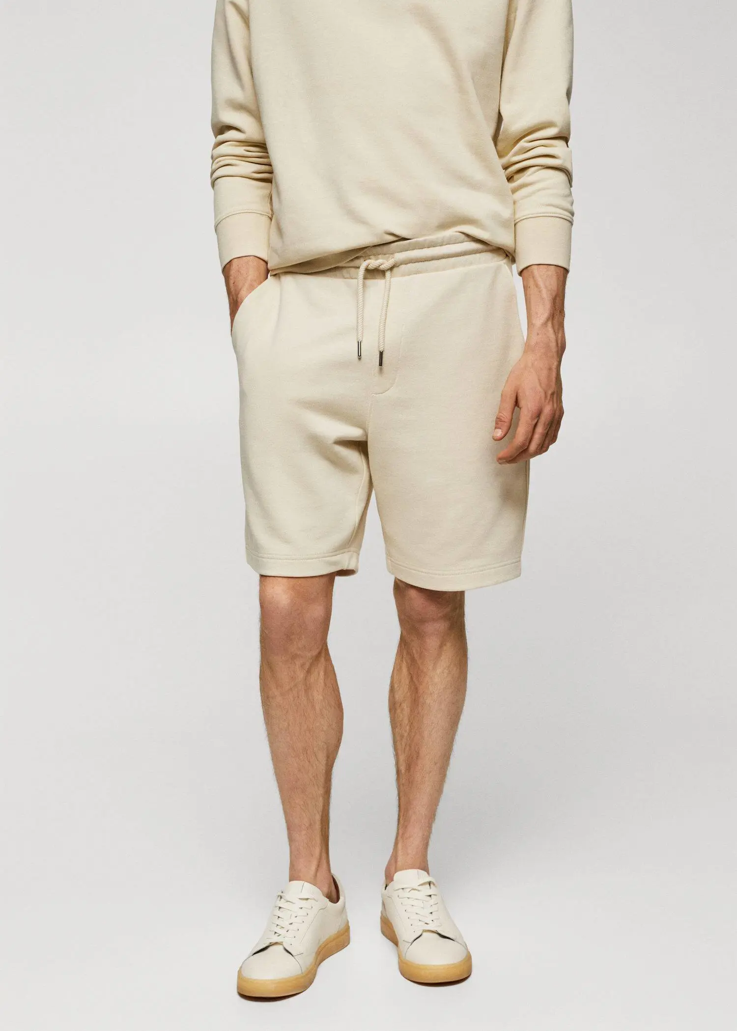 Mango Jogger cotton Bermuda shorts. a man in white shorts and a beige sweatshirt. 