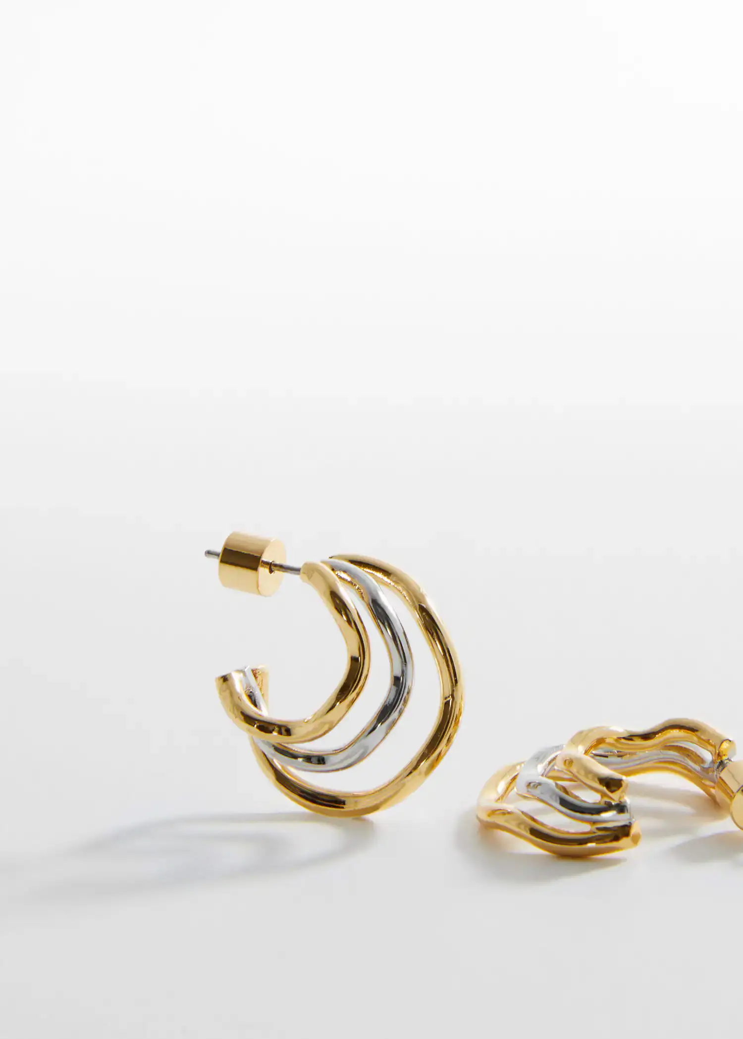 Mango Two-tone hoop earrings. a close up of a pair of earrings on a table 