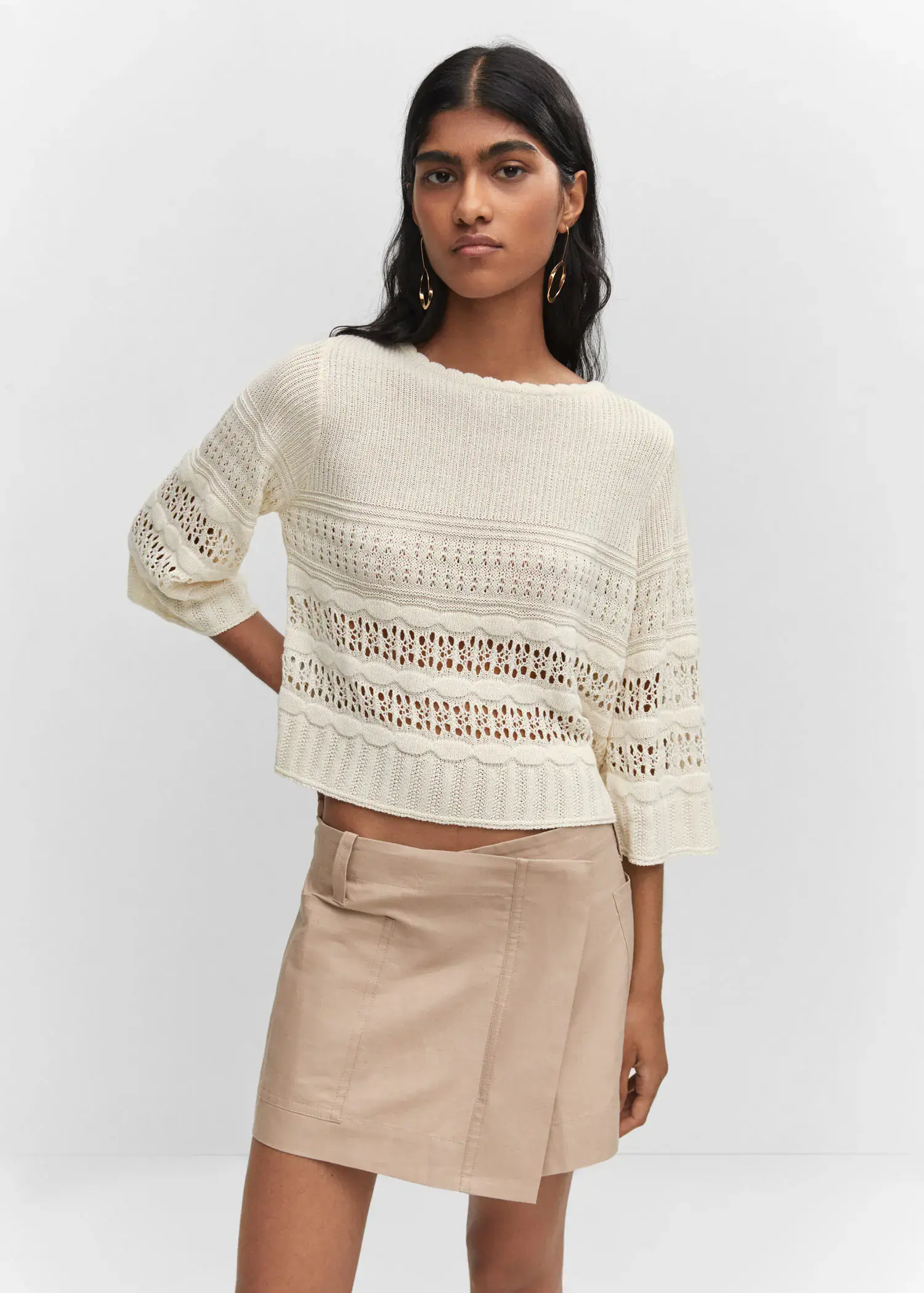 Mango Openwork sweater with flared sleeves. a woman wearing a white sweater and a tan skirt. 