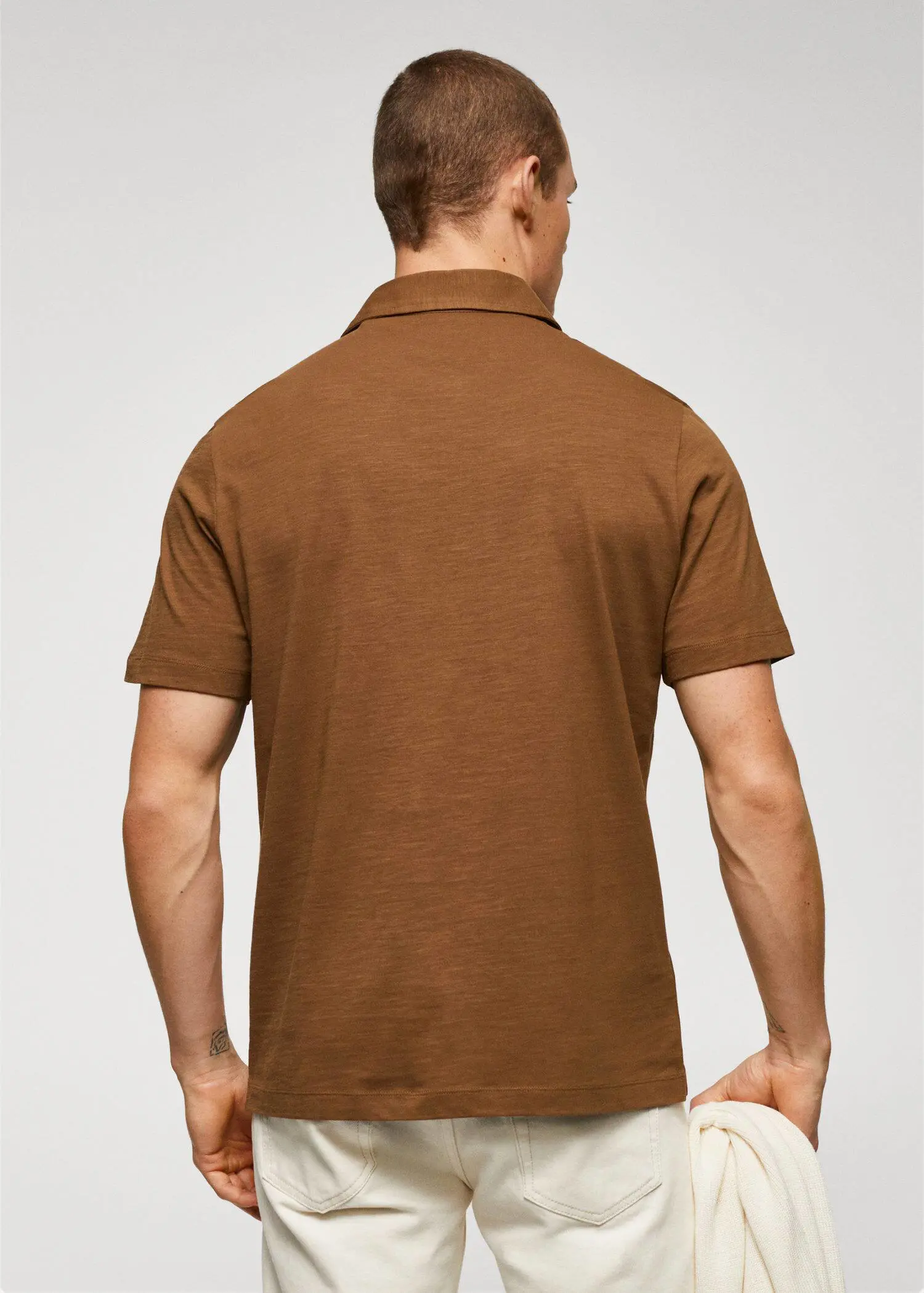 Mango 100% cotton basic polo shirt . a man wearing a brown polo shirt standing in front of a white wall. 