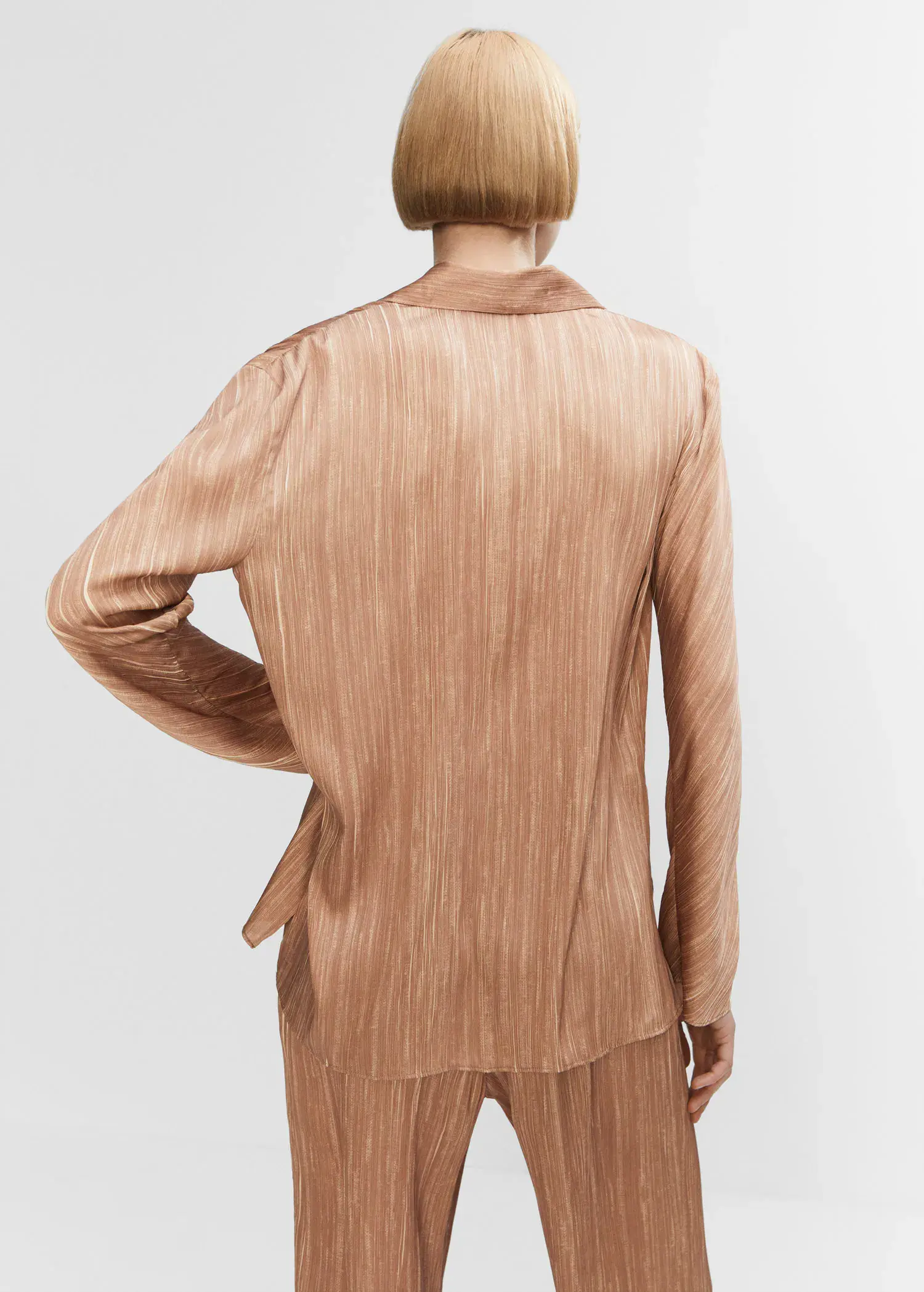 Mango Satin pleated shirt. a person wearing a tan suit standing next to a wall. 