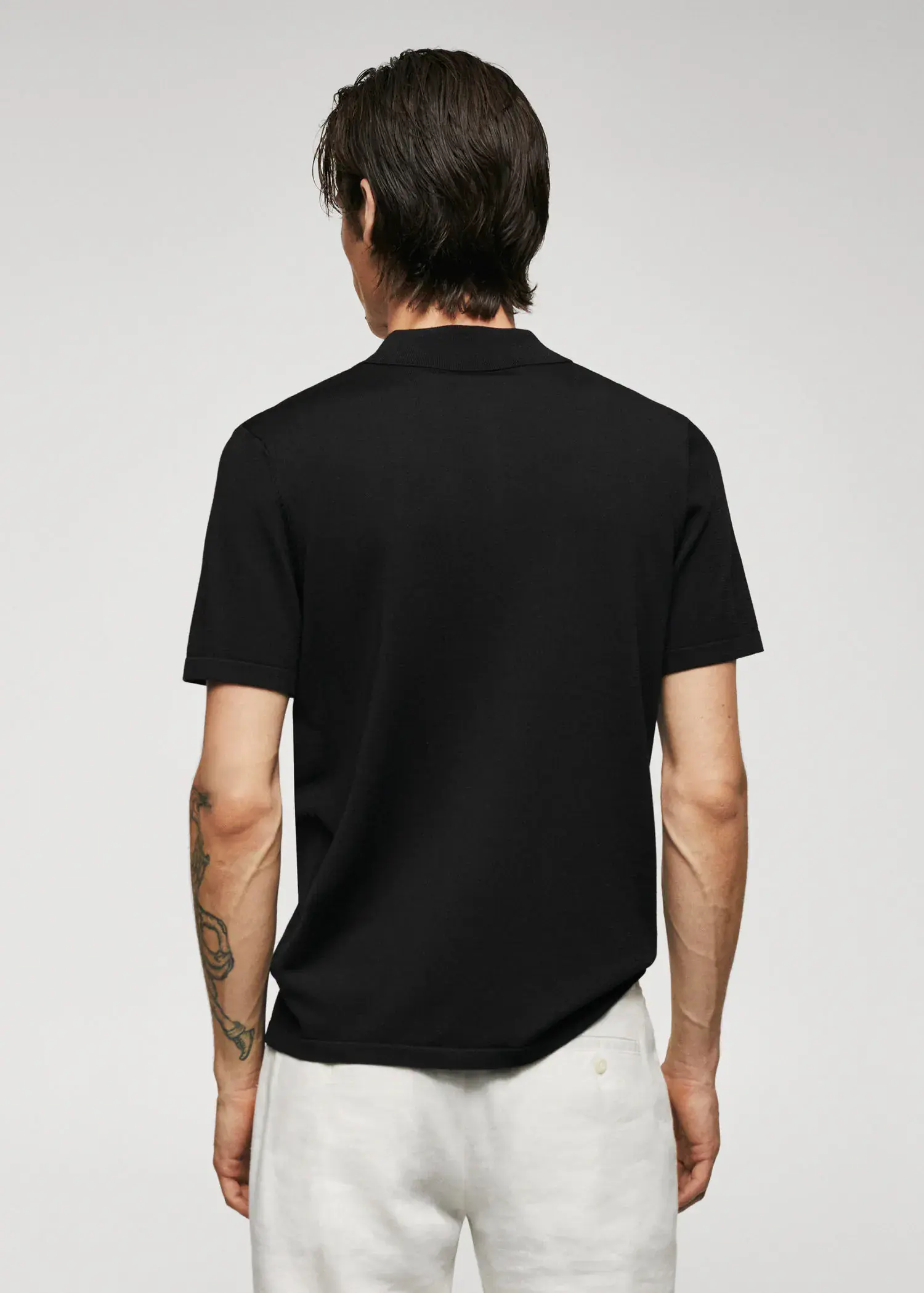Mango Fine-knit polo shirt with zip. a man wearing a black polo shirt and white pants. 