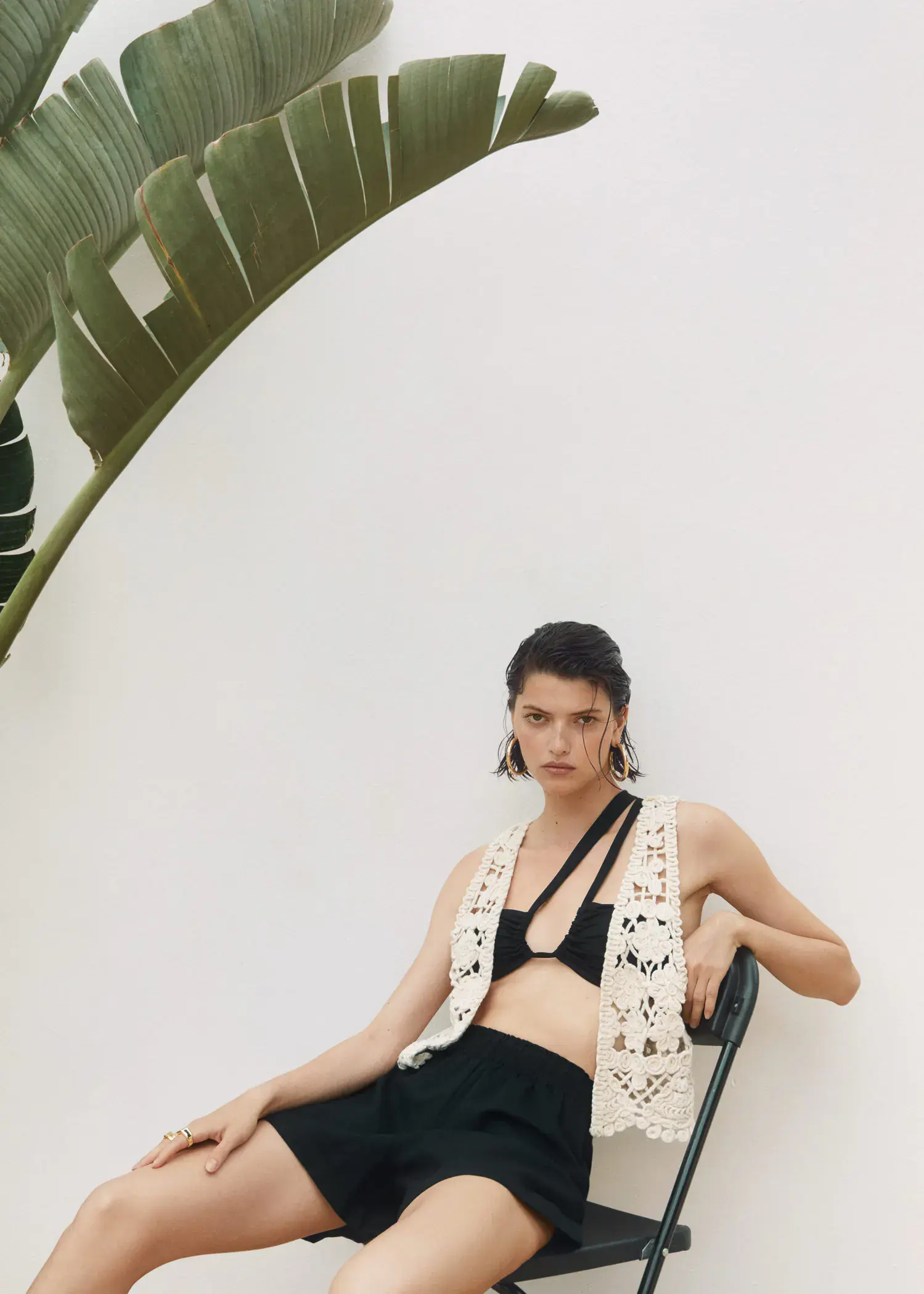 Mango Fringed vest. a woman sitting on a chair in front of a plant. 