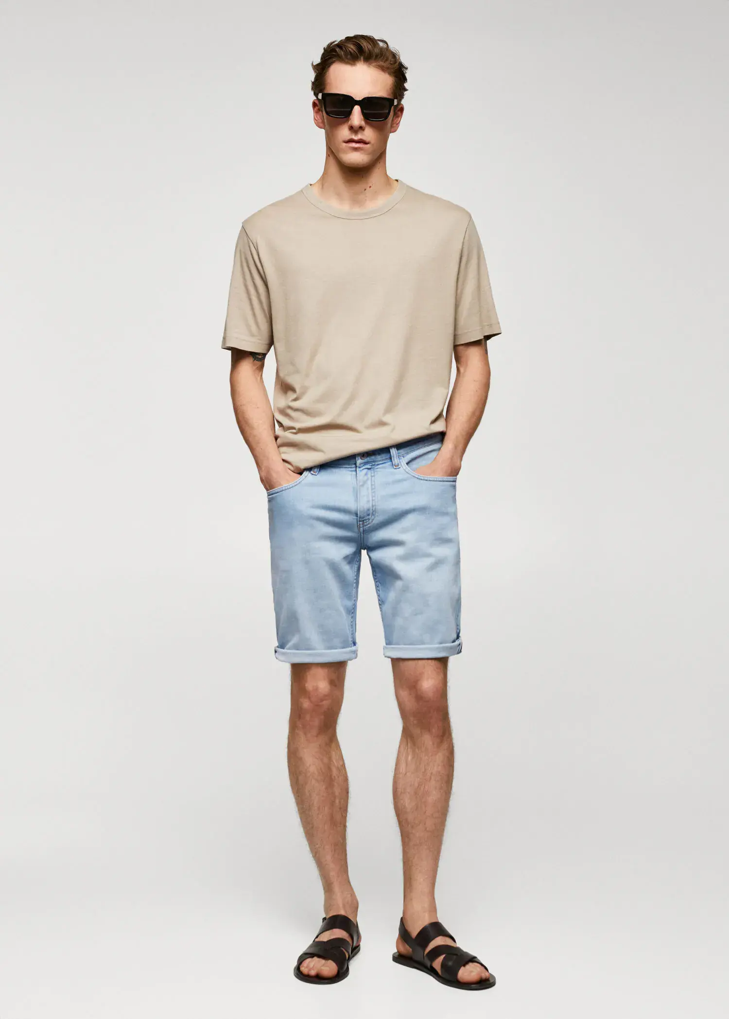 Mango Slim-fit denim bermuda shorts. a young man wearing light blue shorts and a beige t shirt. 