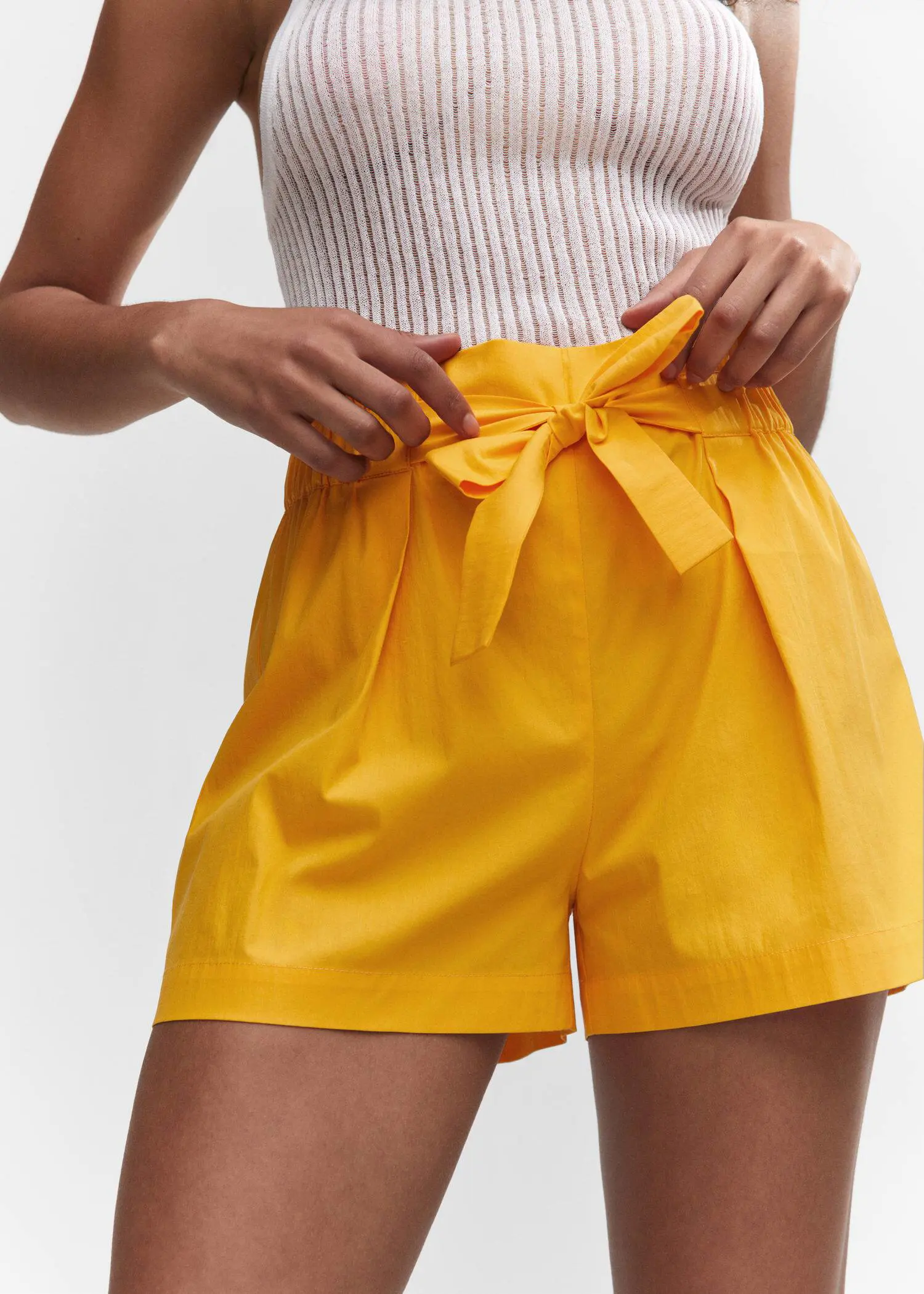 Mango Paperbag shorts with bow. a person wearing a yellow shorts and a white top. 