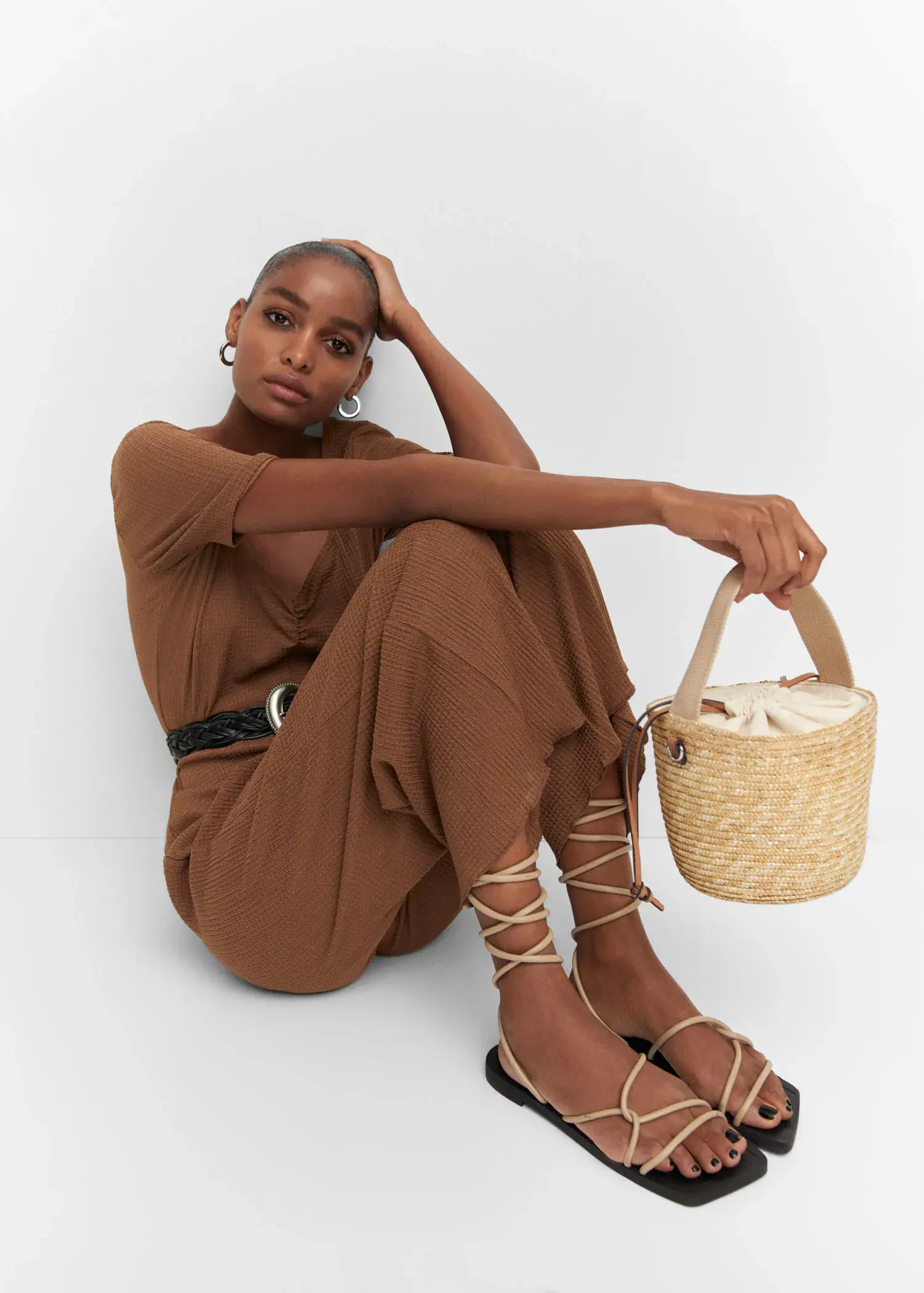 Mango Ruched long jumpsuit. a woman sitting on the ground holding a bag. 
