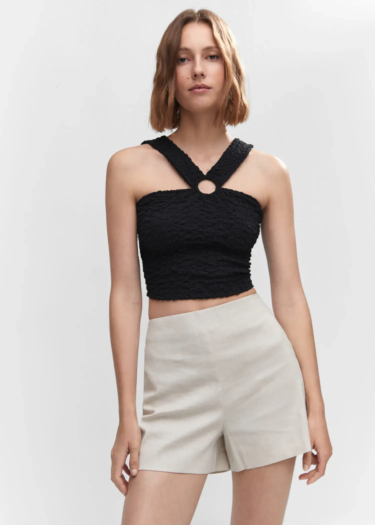 Mango Textured top with ring detail. a woman wearing a black top and white shorts. 