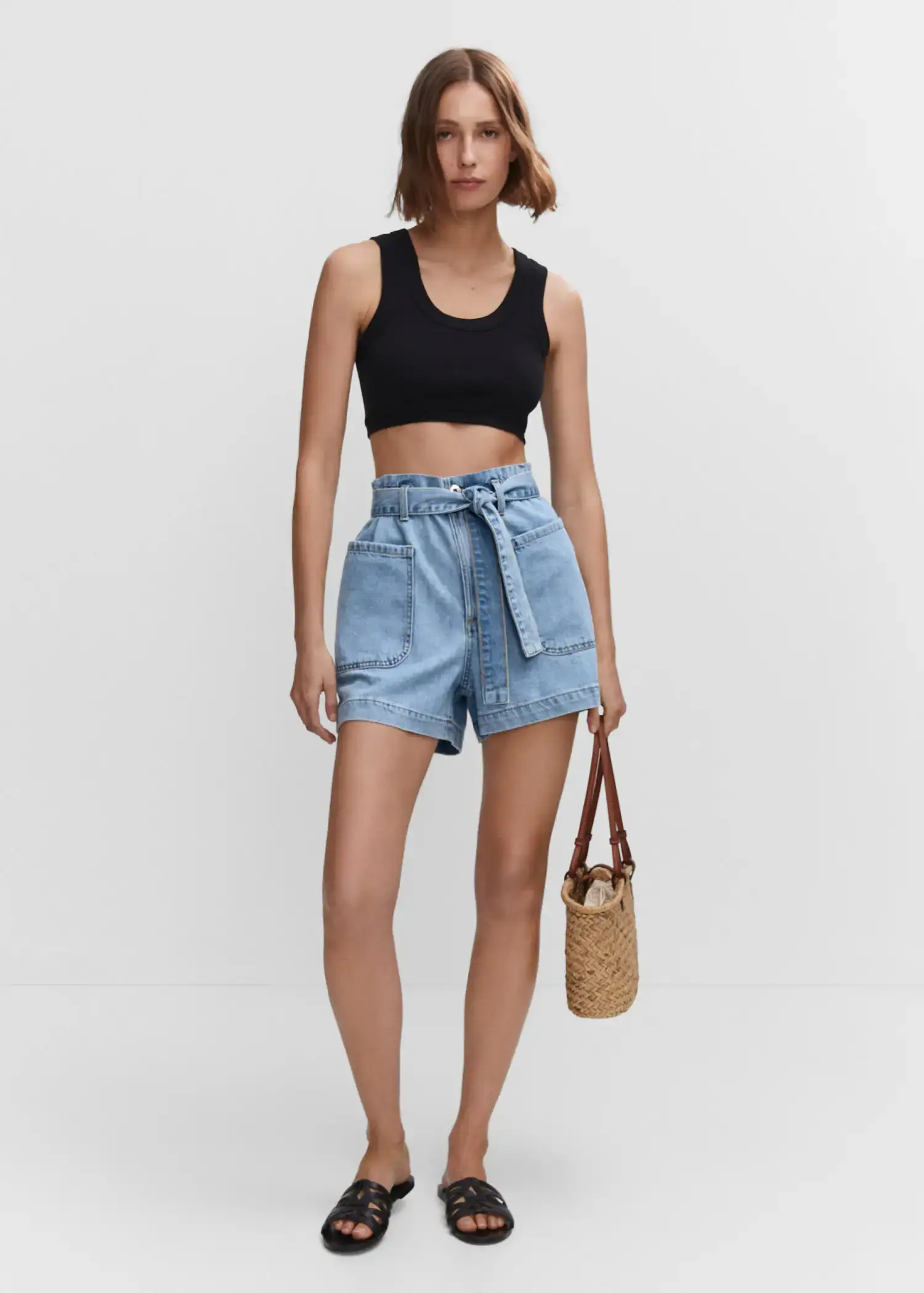 Mango Paperbag shorts with belt. a woman in a black crop top holding a bag. 