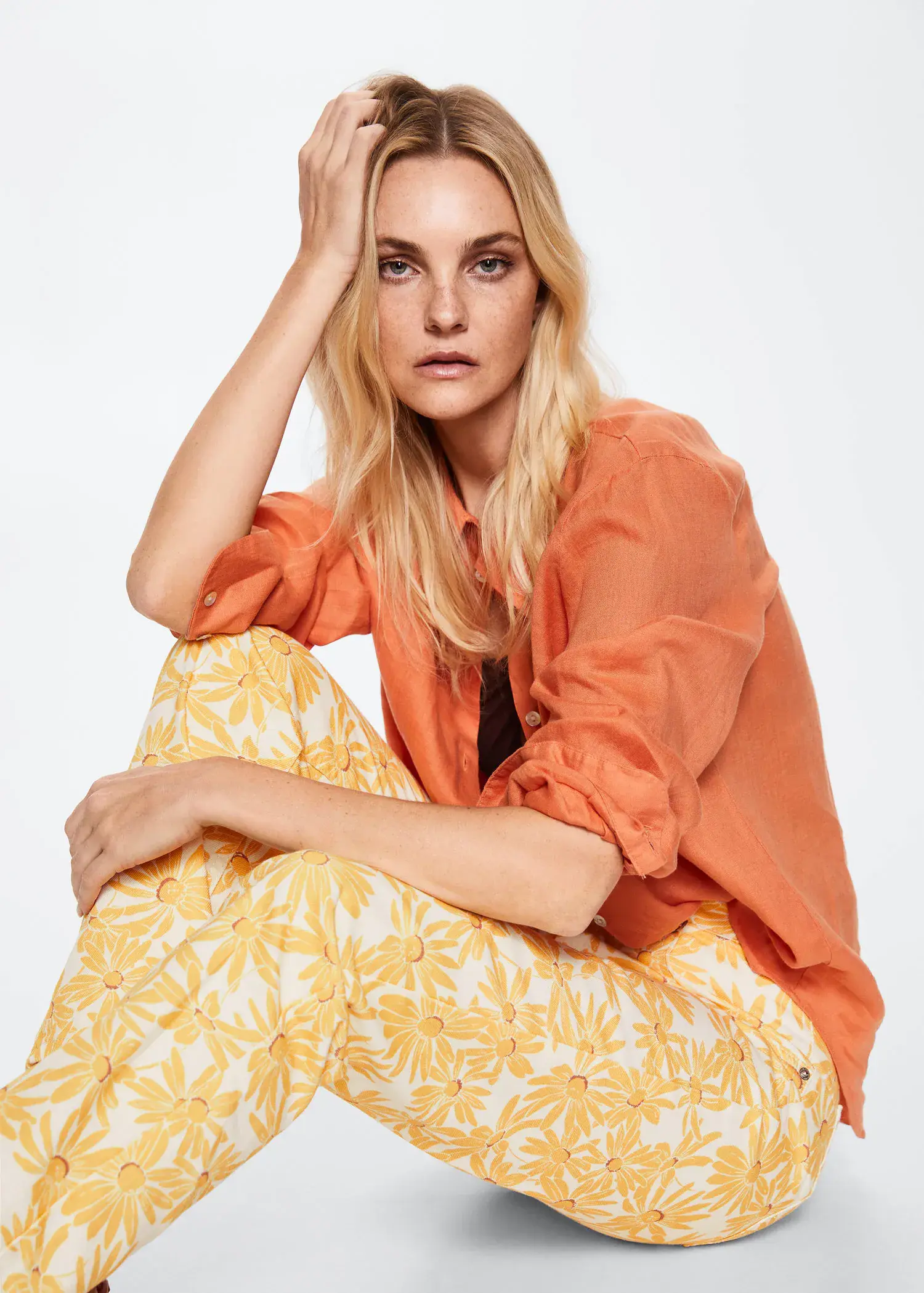 Mango Printed straight jeans. a woman sitting on top of a chair wearing a orange shirt. 