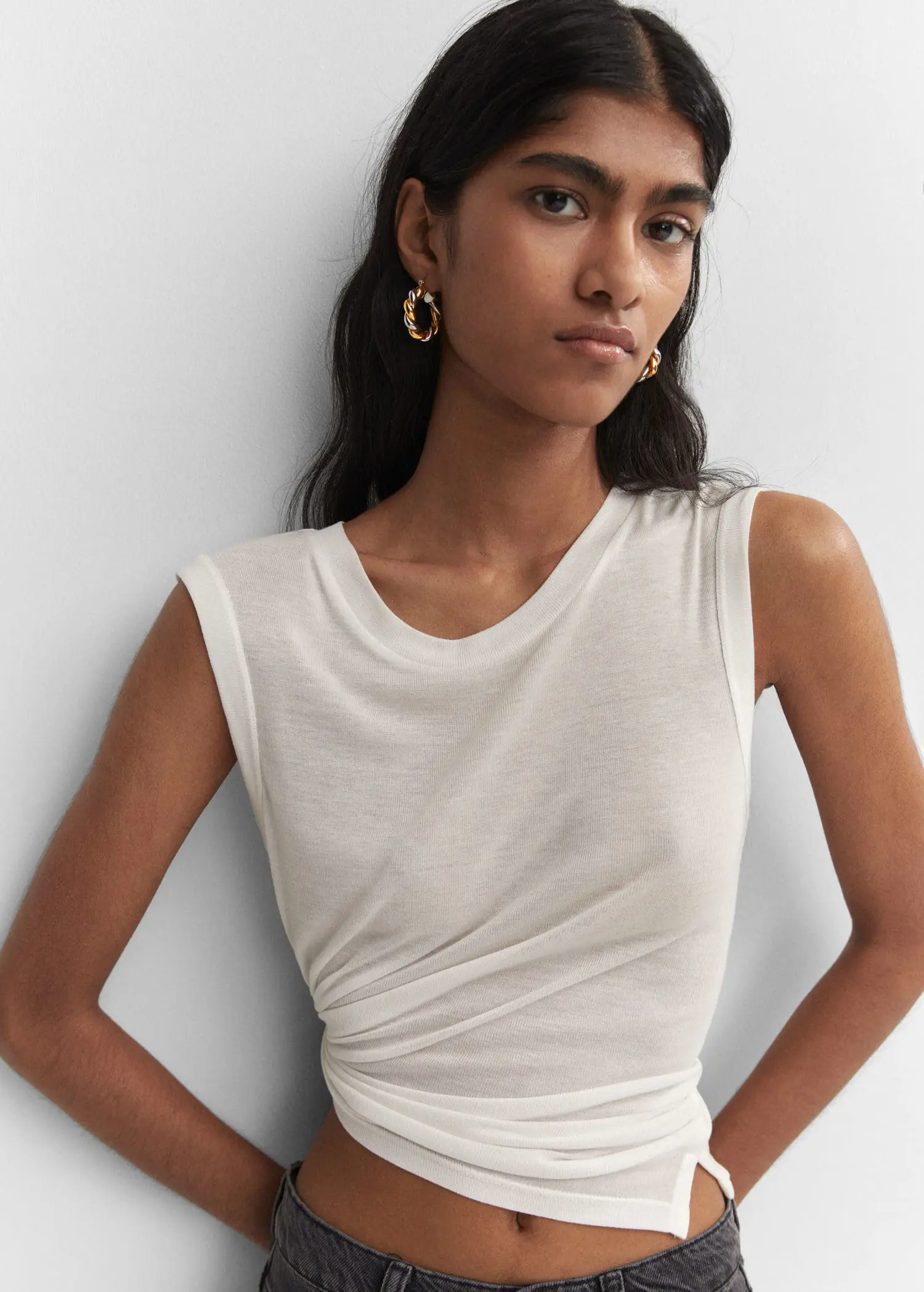 Mango Intertwined hoop earrings. a woman in a white shirt and a white wall 