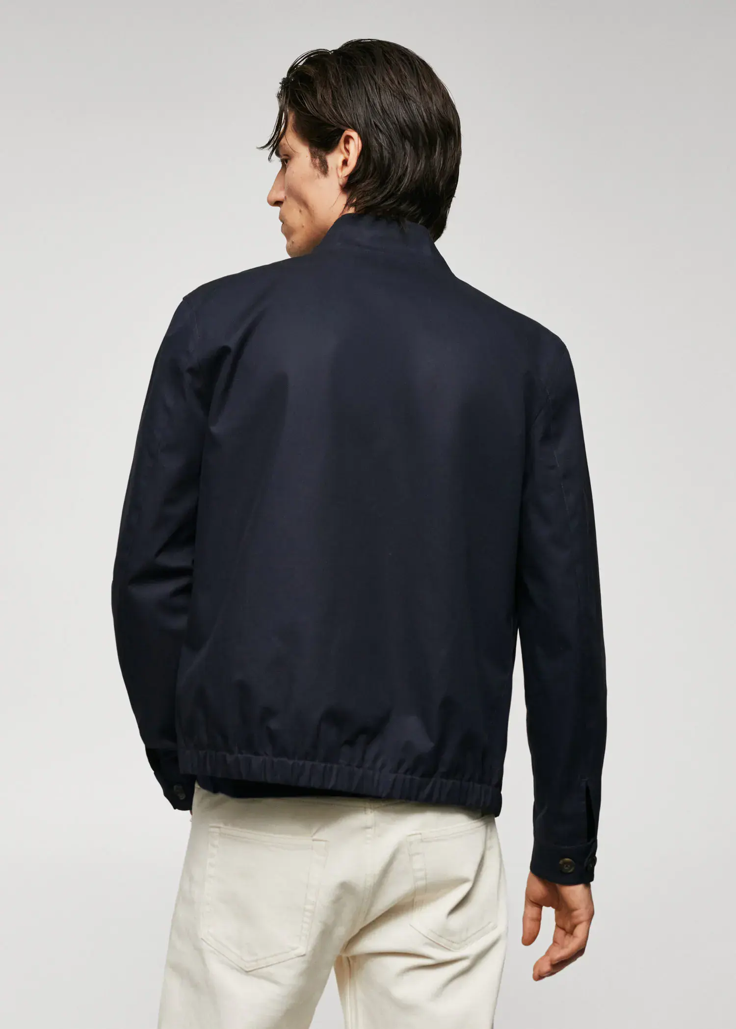 Mango 100% cotton bomber jacket. a man wearing a black jacket standing in front of a white wall. 