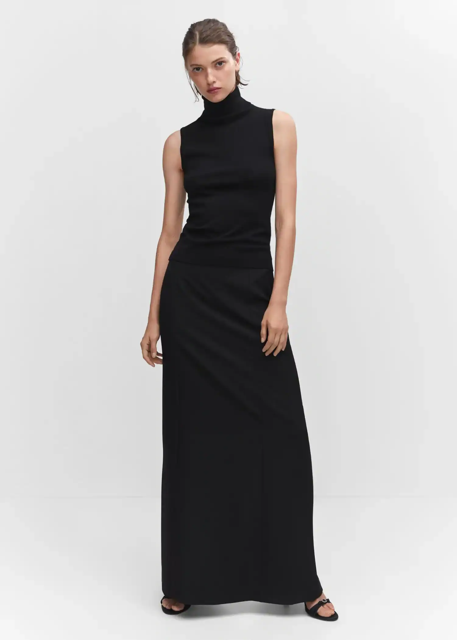 Mango Flowy long skirt. a woman wearing a black dress standing in a room. 