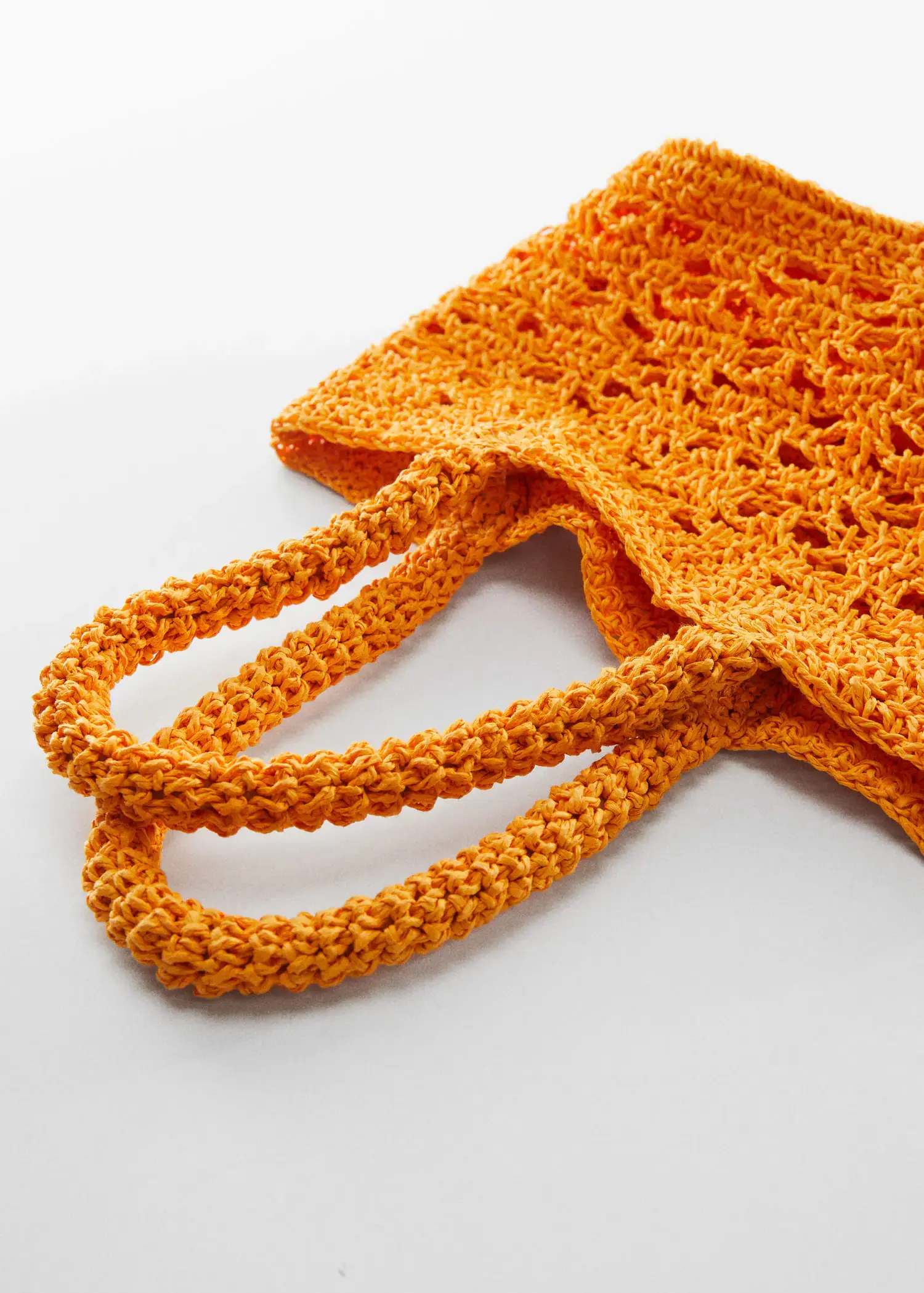 Mango Double-handle raffia bag. an orange crocheted bag with handles on a white surface. 