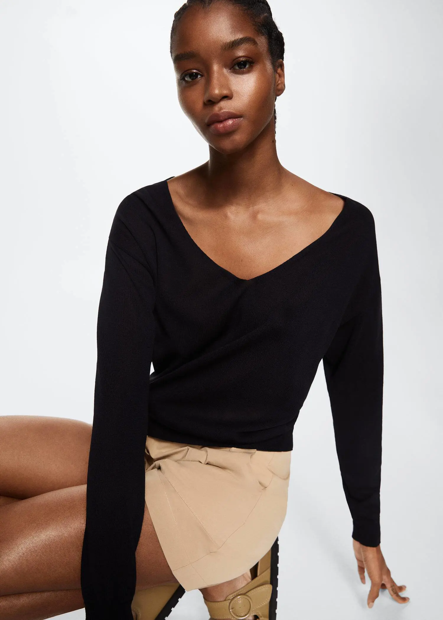 Mango V-neck knit sweater. a woman wearing a black top and beige shorts. 