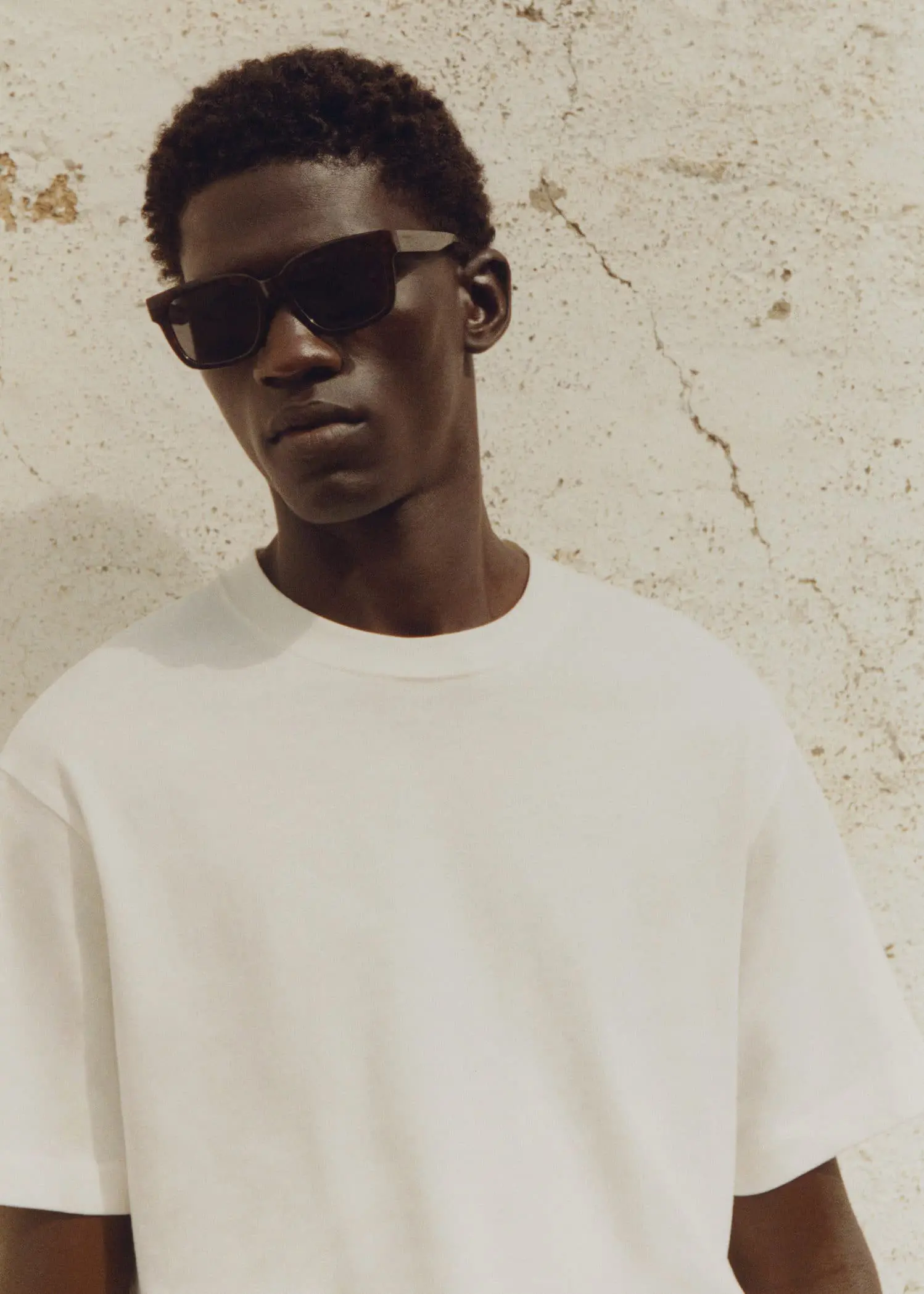 Mango Polarised sunglasses. a young man wearing sunglasses and a white shirt. 