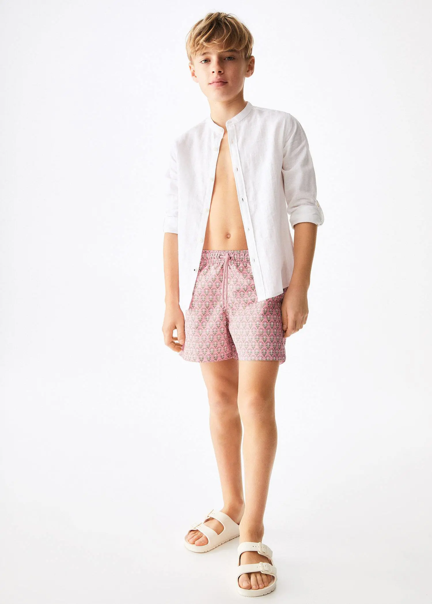 Mango KIDS/ Floral print swimsuit. a young man wearing a white shirt and pink shorts. 