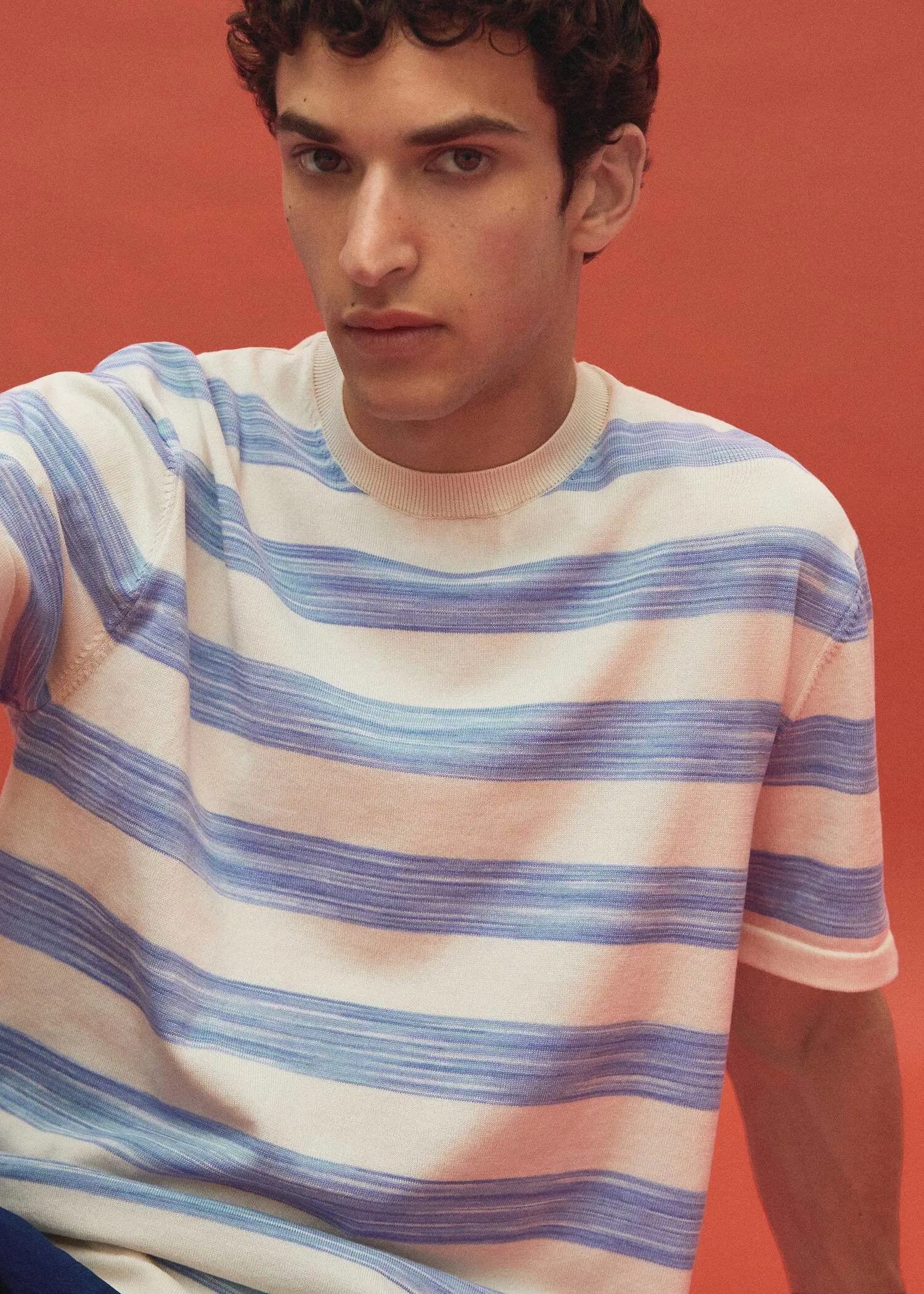 Mango Striped jersey T-shirt. a young man wearing a striped t-shirt in front of an orange wall. 