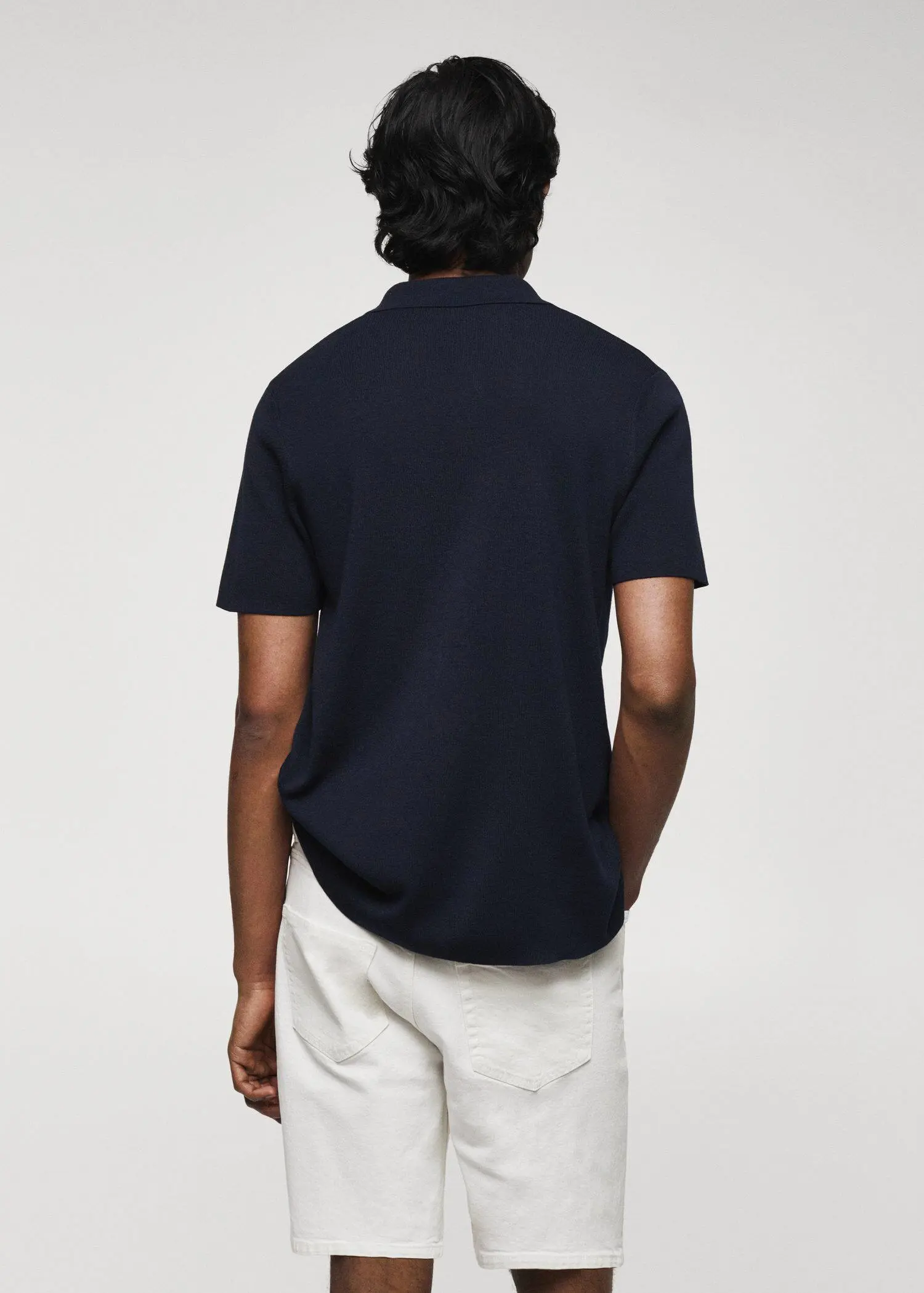 Mango Fine-knit polo shirt. a man wearing a black polo shirt and white shorts. 