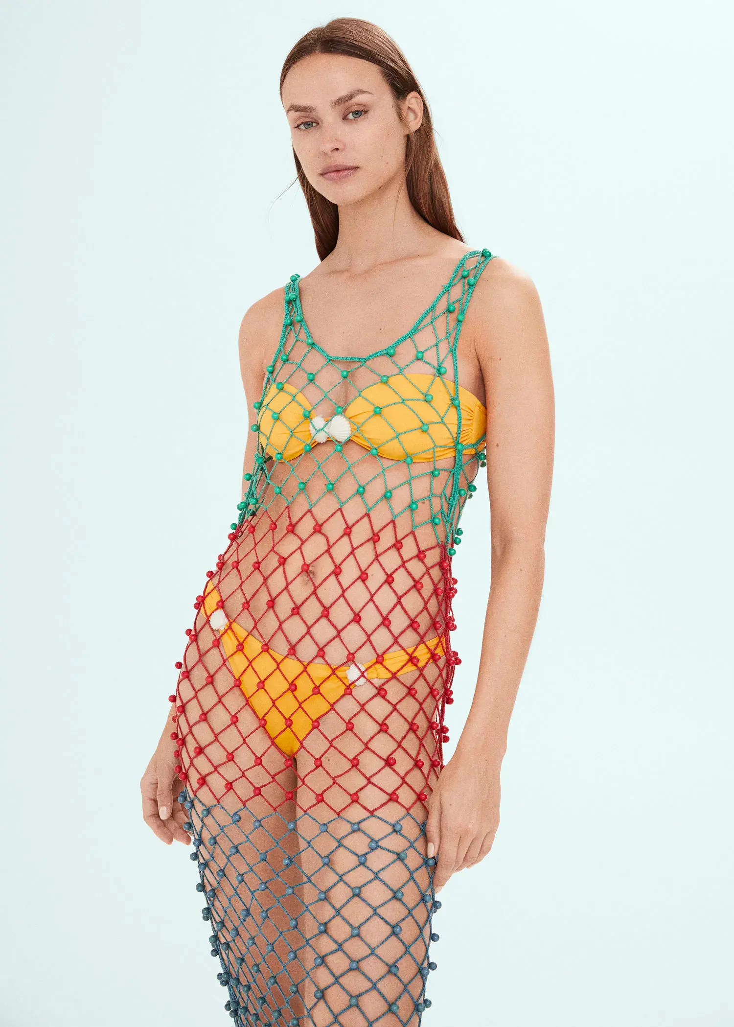 Mango Multi-coloured net dress with beads. a woman in a colorful bathing suit standing in front of a wall. 