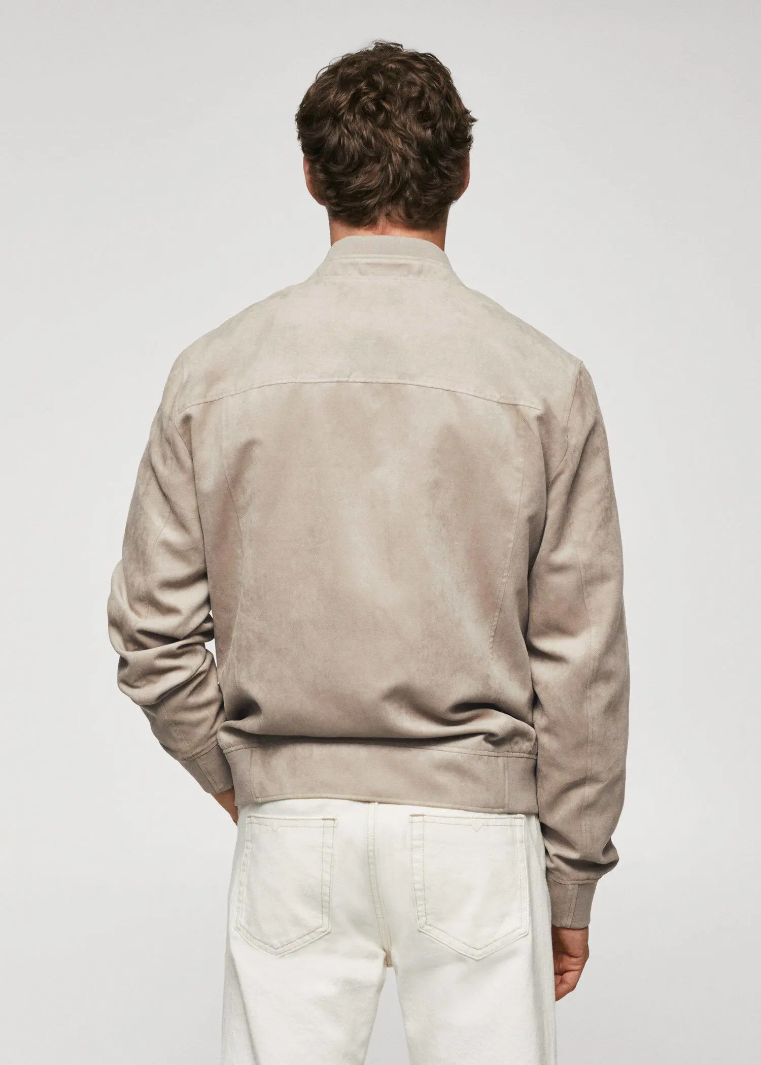 Mango Suede-effect bomber jacket. a man wearing a tan jacket standing in front of a wall. 