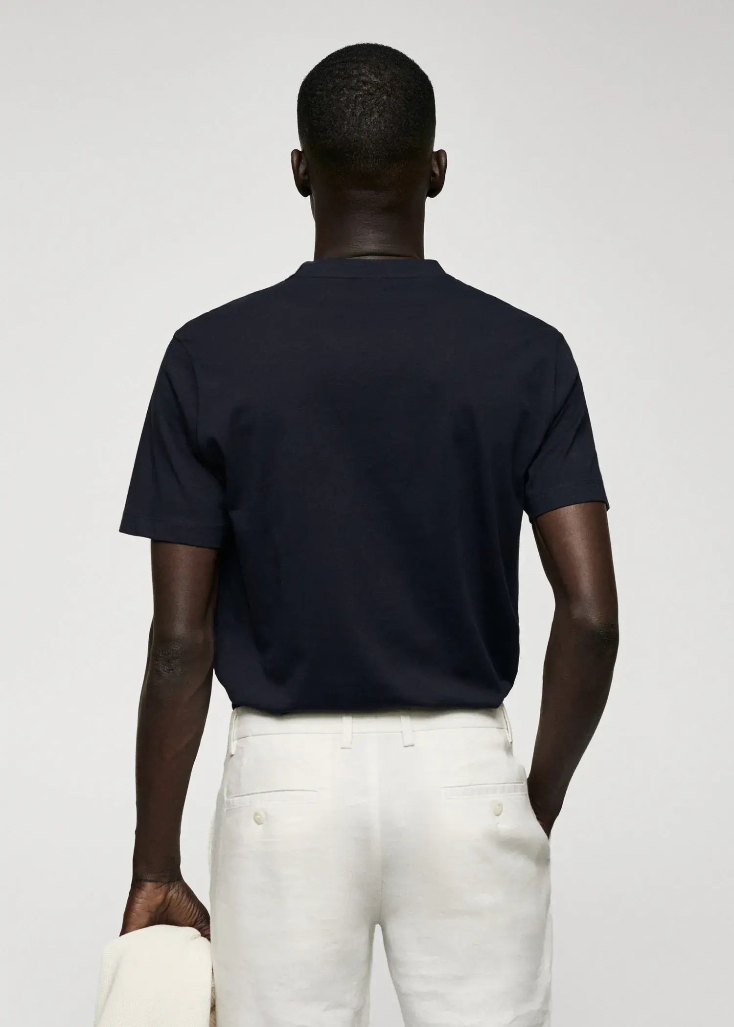 Mango Basic cotton V-neck T-shirt. a man wearing a black shirt and white pants. 