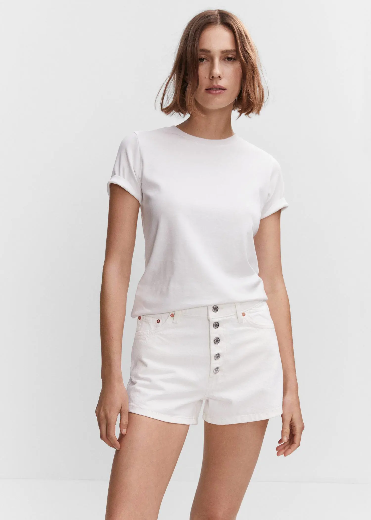 Mango Denim shorts with buttons. a woman wearing white shorts and a white t-shirt. 
