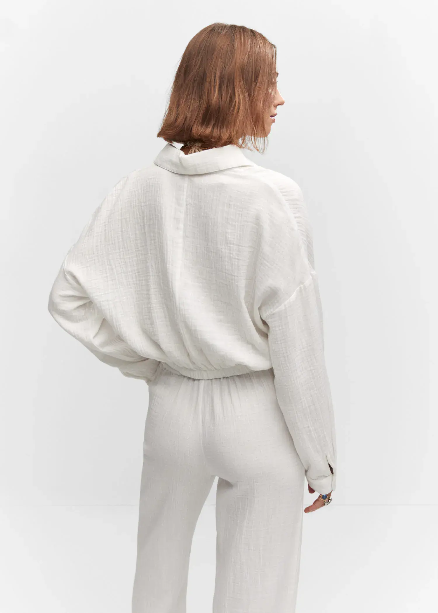 Mango Textured blouse with knot detail. a woman wearing all white standing in front of a white wall. 