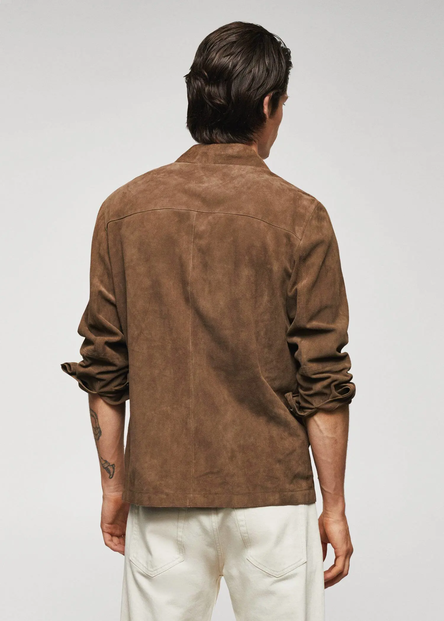 Mango 100% suede leather jacket. a man wearing a brown jacket standing in front of a wall. 