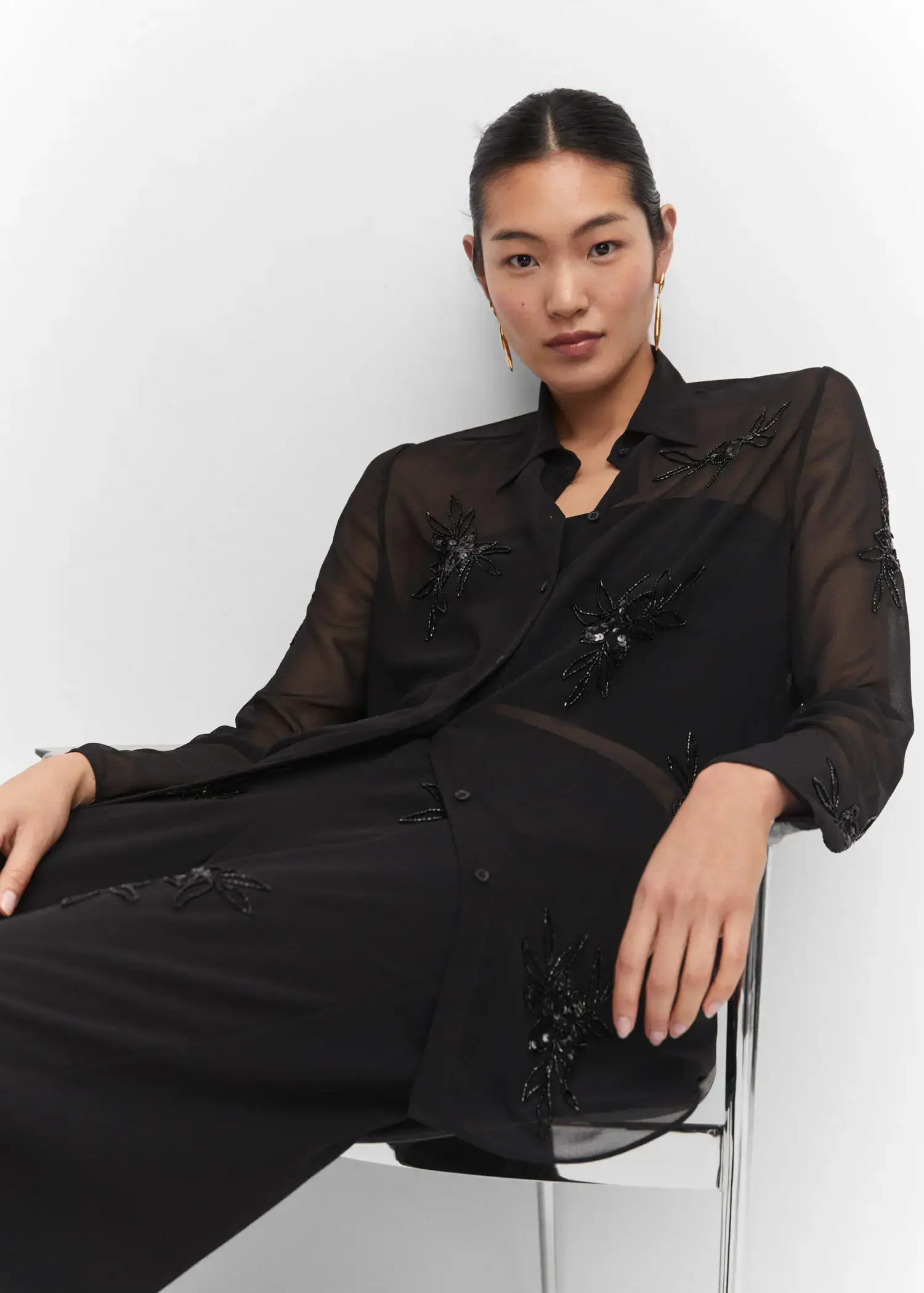Mango Shirt with bead detail. a woman sitting on the ground wearing a black dress. 