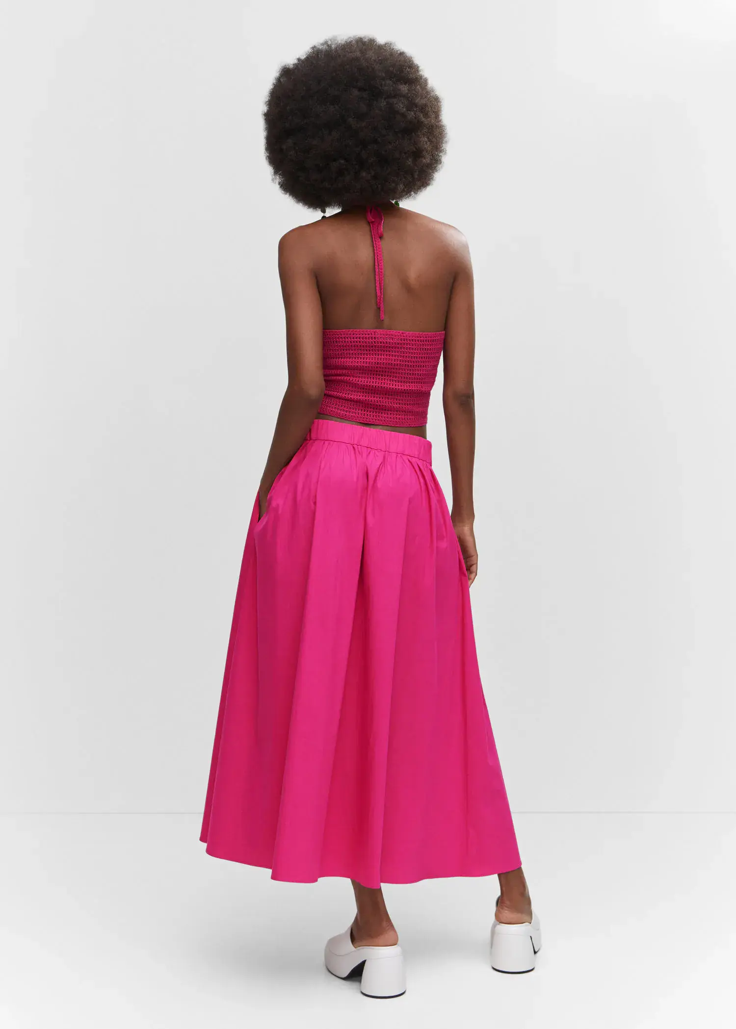 Mango Pleat detail long skirt. a woman wearing a pink dress standing next to a wall. 
