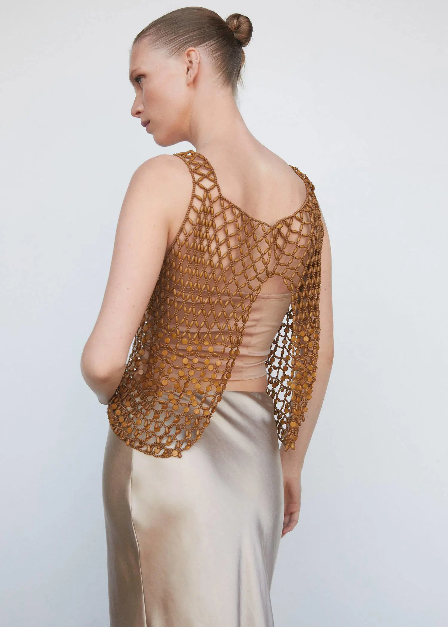 Mango Beaded open-work top. a woman wearing a brown crocheted top. she is standing in front of a wall. 
