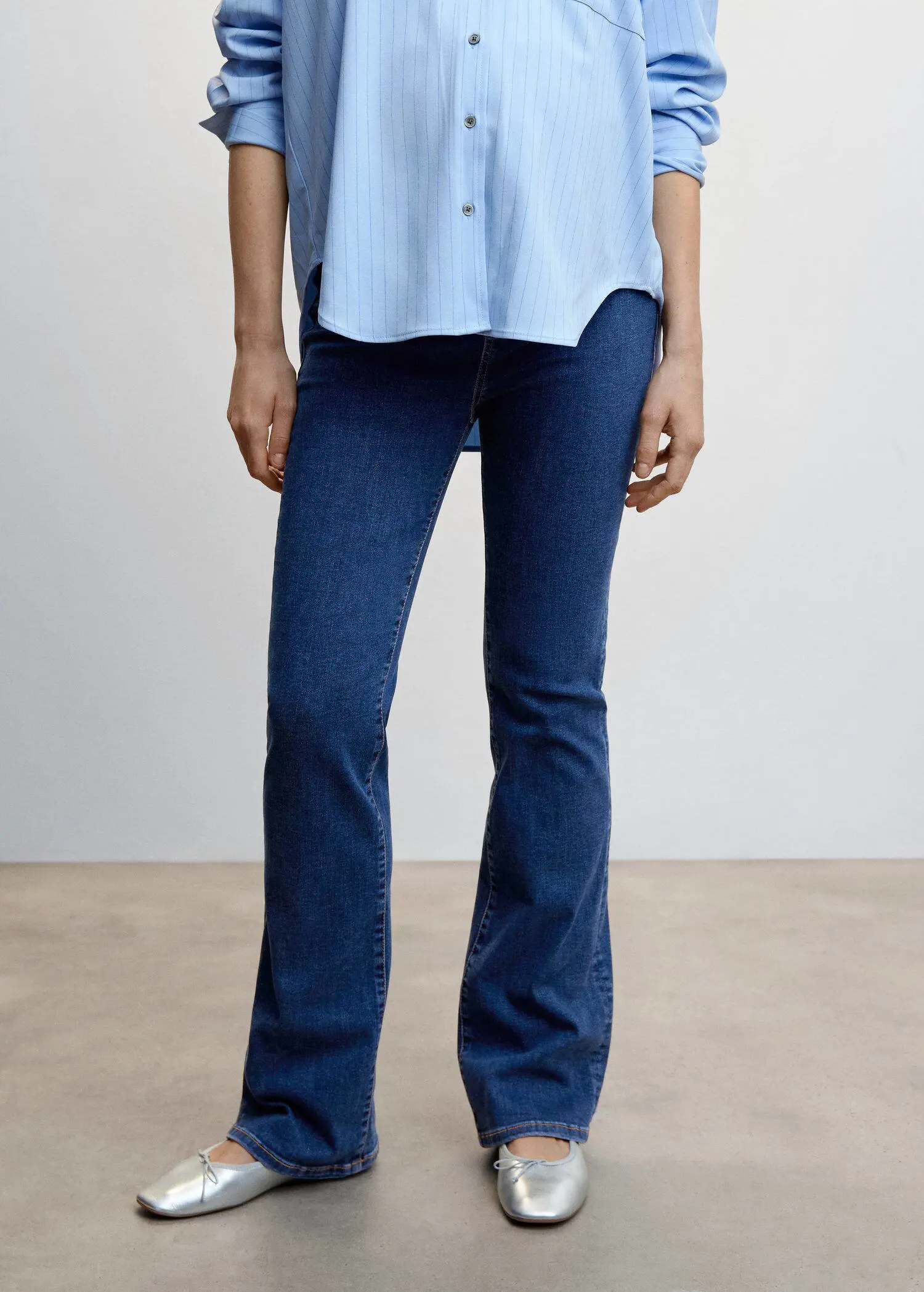 Mango Maternity flared jeans. a woman standing in front of a white wall. 