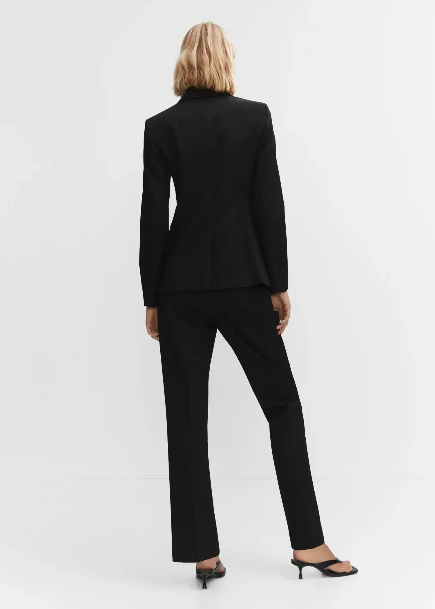 Mango Fitted suit jacket. a woman in a black suit is posing for a picture. 