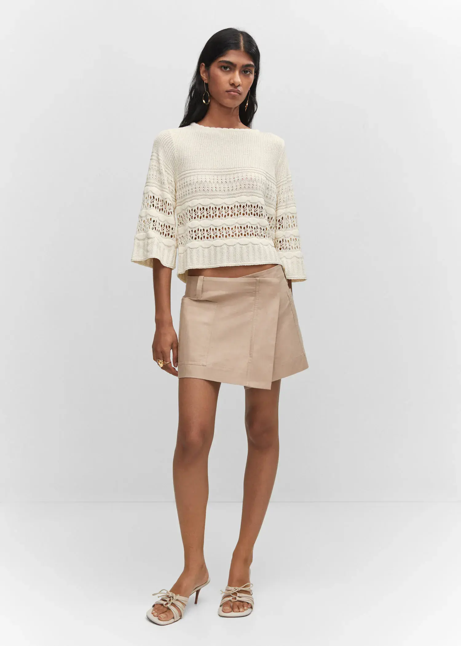 Mango Openwork sweater with flared sleeves. a woman in a white top and a skirt. 