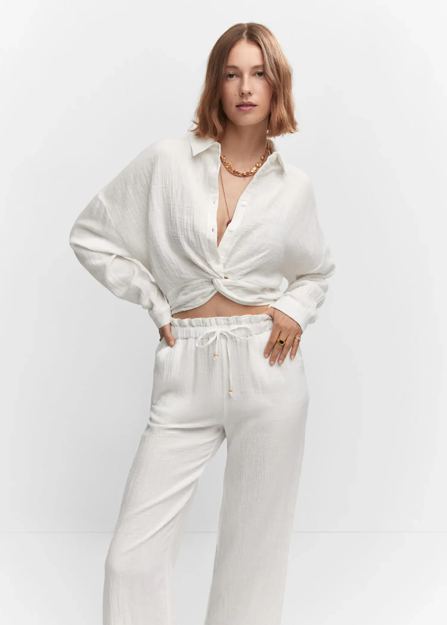 Mango Textured blouse with knot detail. a woman in a white outfit standing in front of a white wall. 