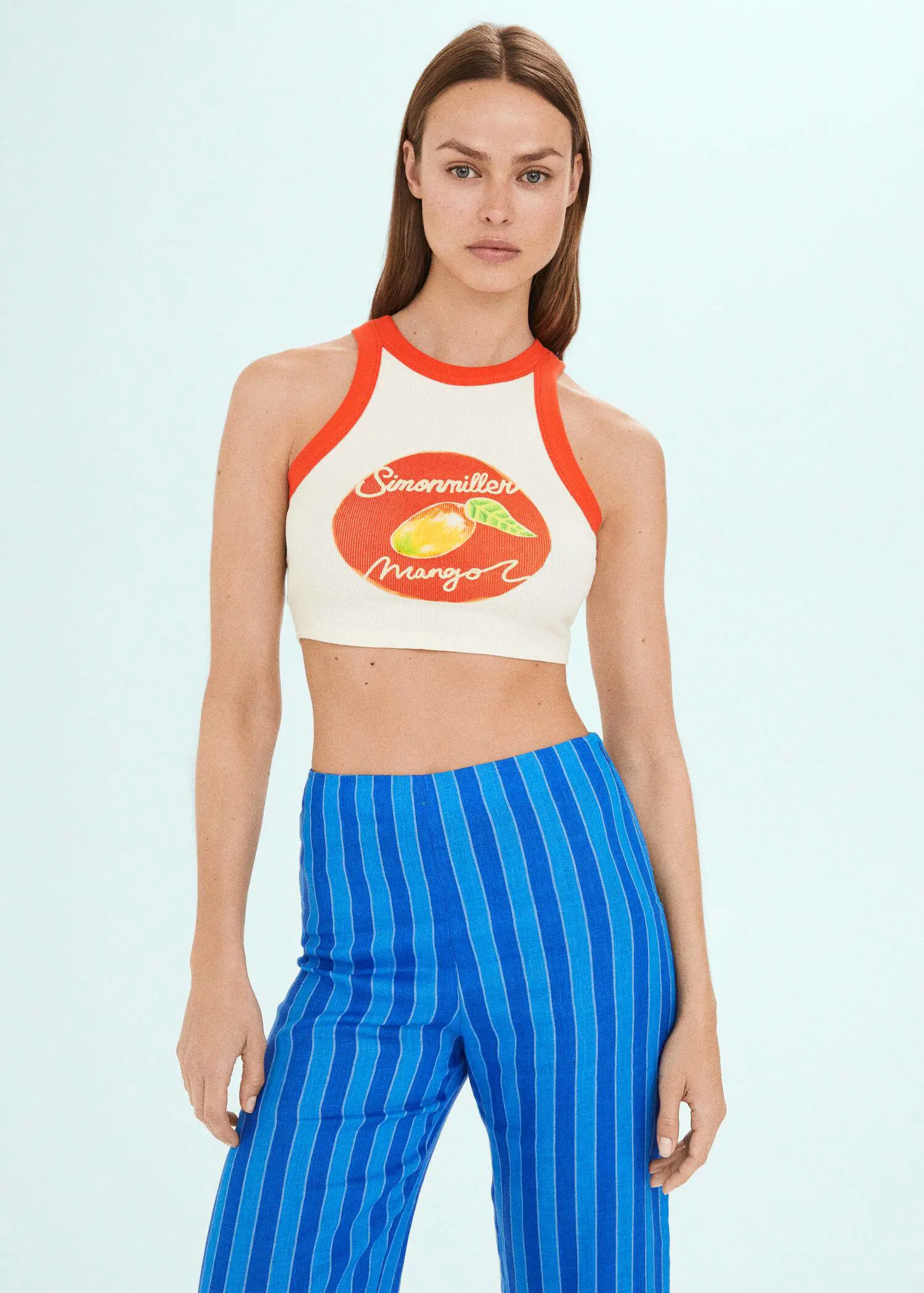 Mango Printed halter-neck cropped top. a woman wearing a white crop top and blue striped pants. 