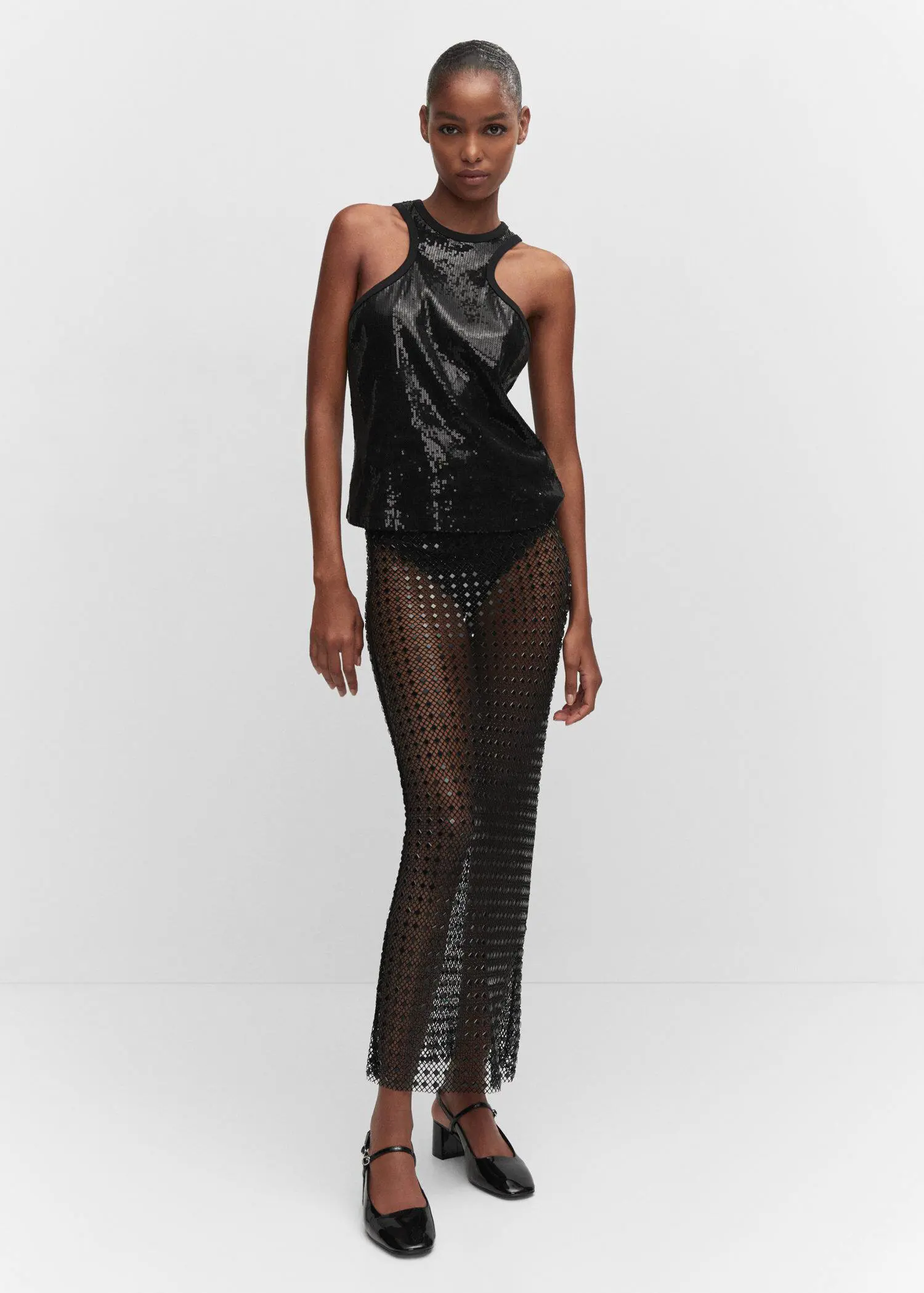 Mango Sequin halter top. a woman in a black dress standing in front of a white wall. 