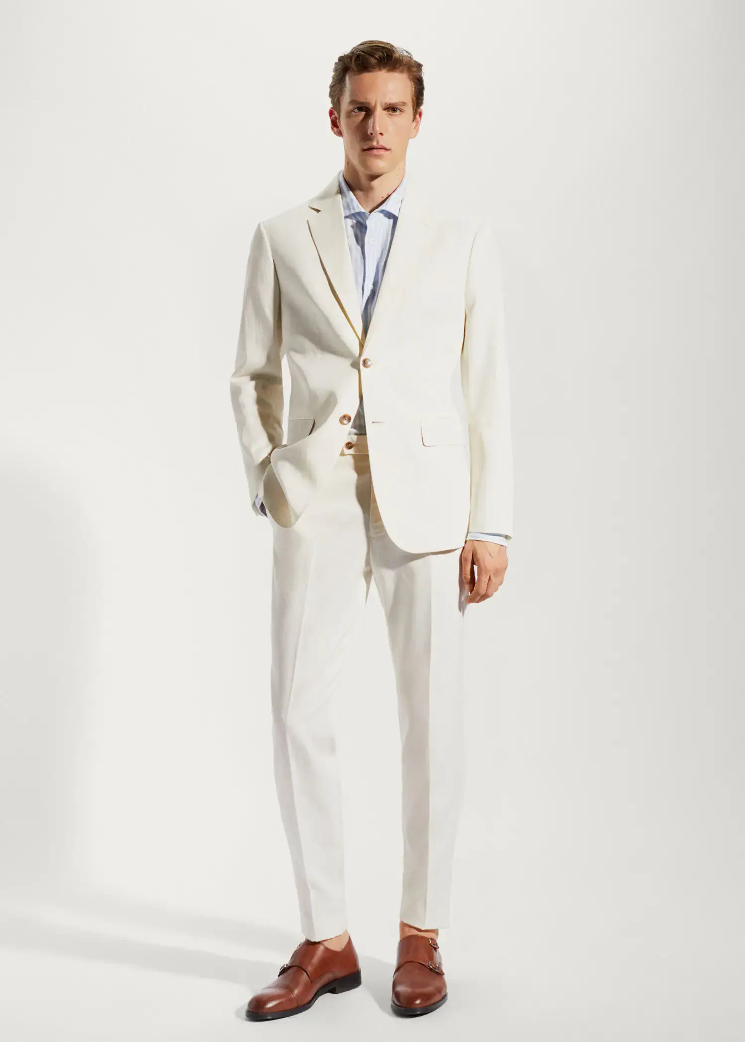 Mango 100% linen suit trousers. a man in a white suit standing in front of a white wall. 