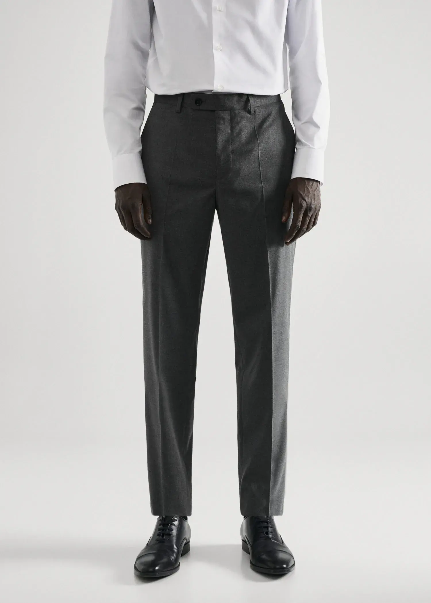 Mango Stretch fabric slim-fit suit trousers. a man wearing a suit standing in front of a white wall. 