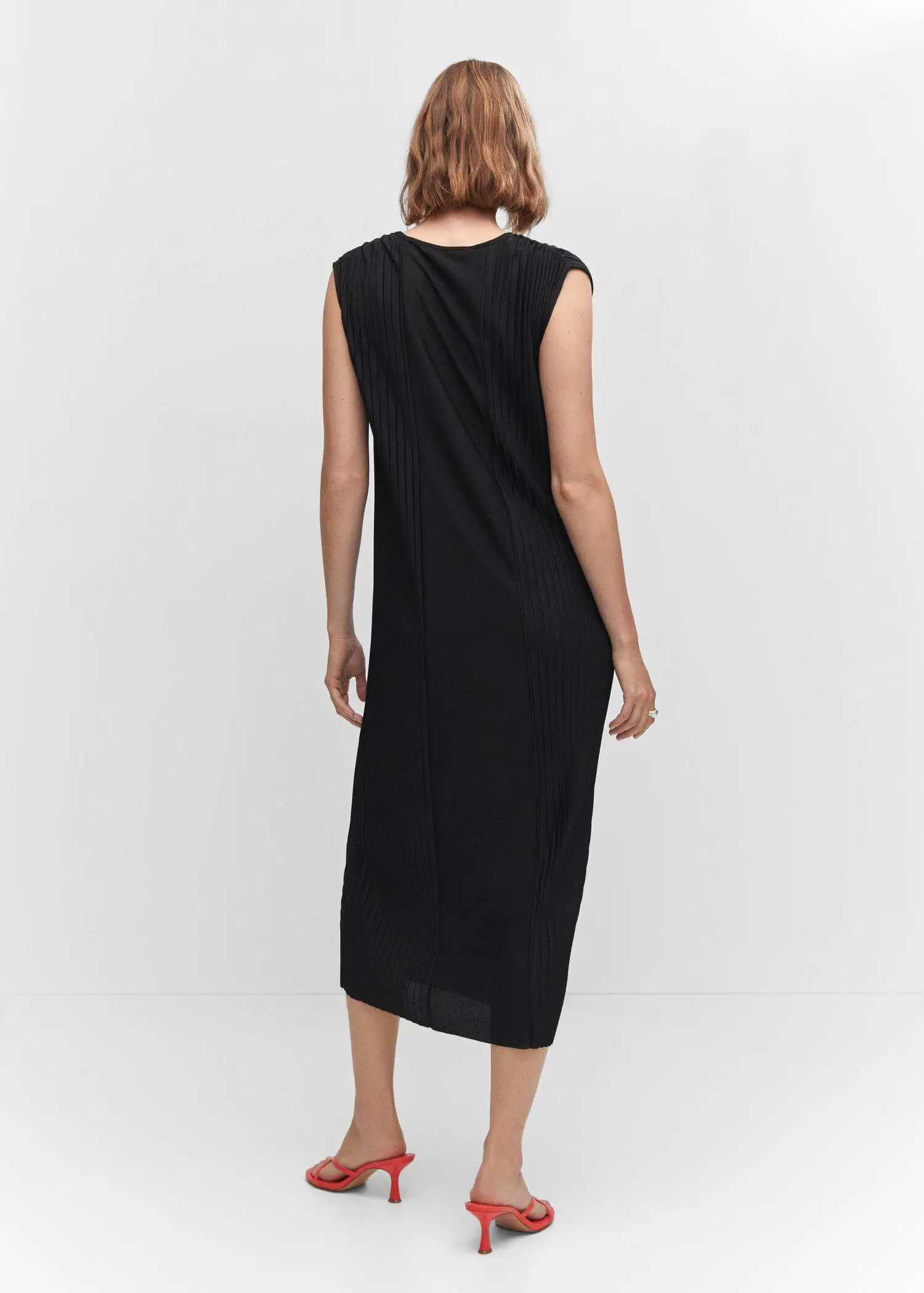 Mango Pleated detail dress. a person wearing a black dress standing in a room. 