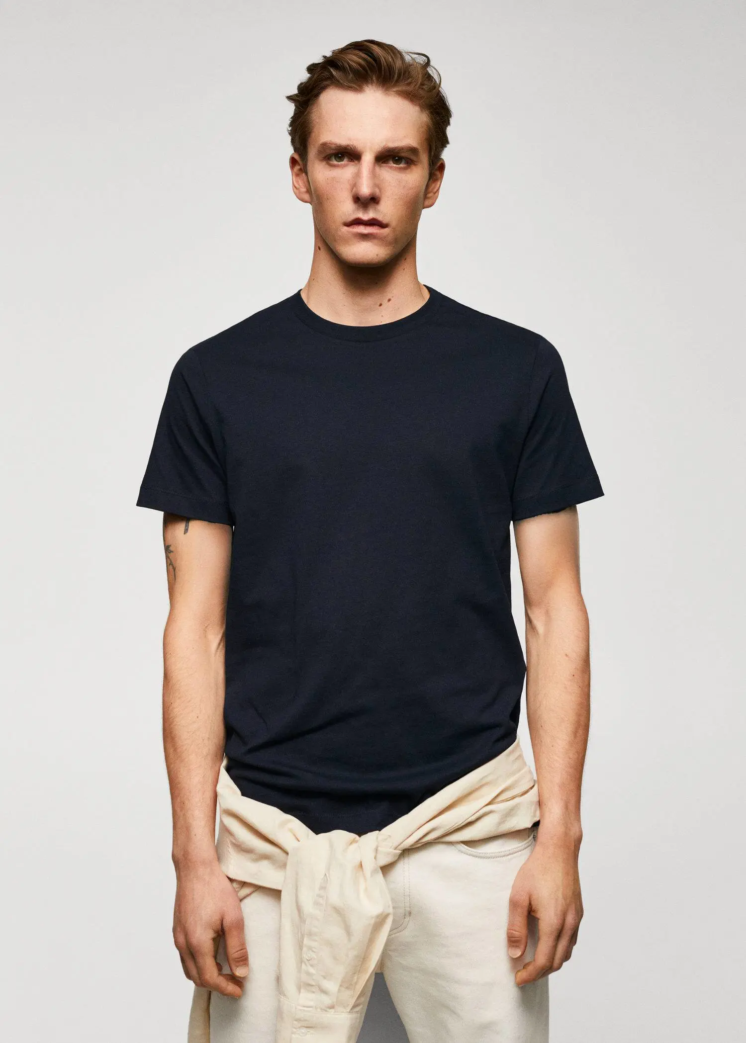 Mango Basic cotton stretch T-shirt. a man wearing a black shirt and beige shorts. 