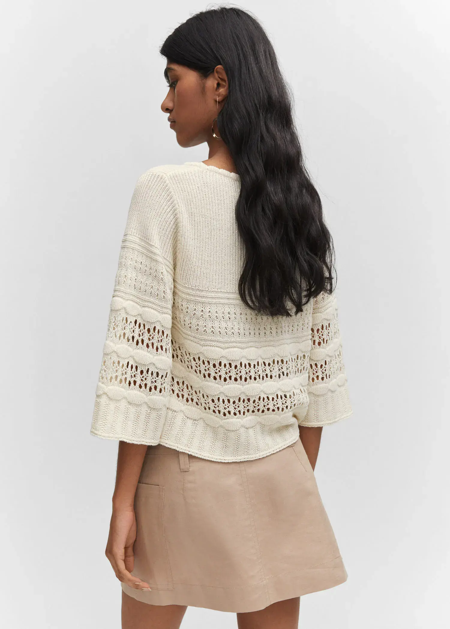 Mango Openwork sweater with flared sleeves. a woman wearing a white sweater and a tan skirt. 