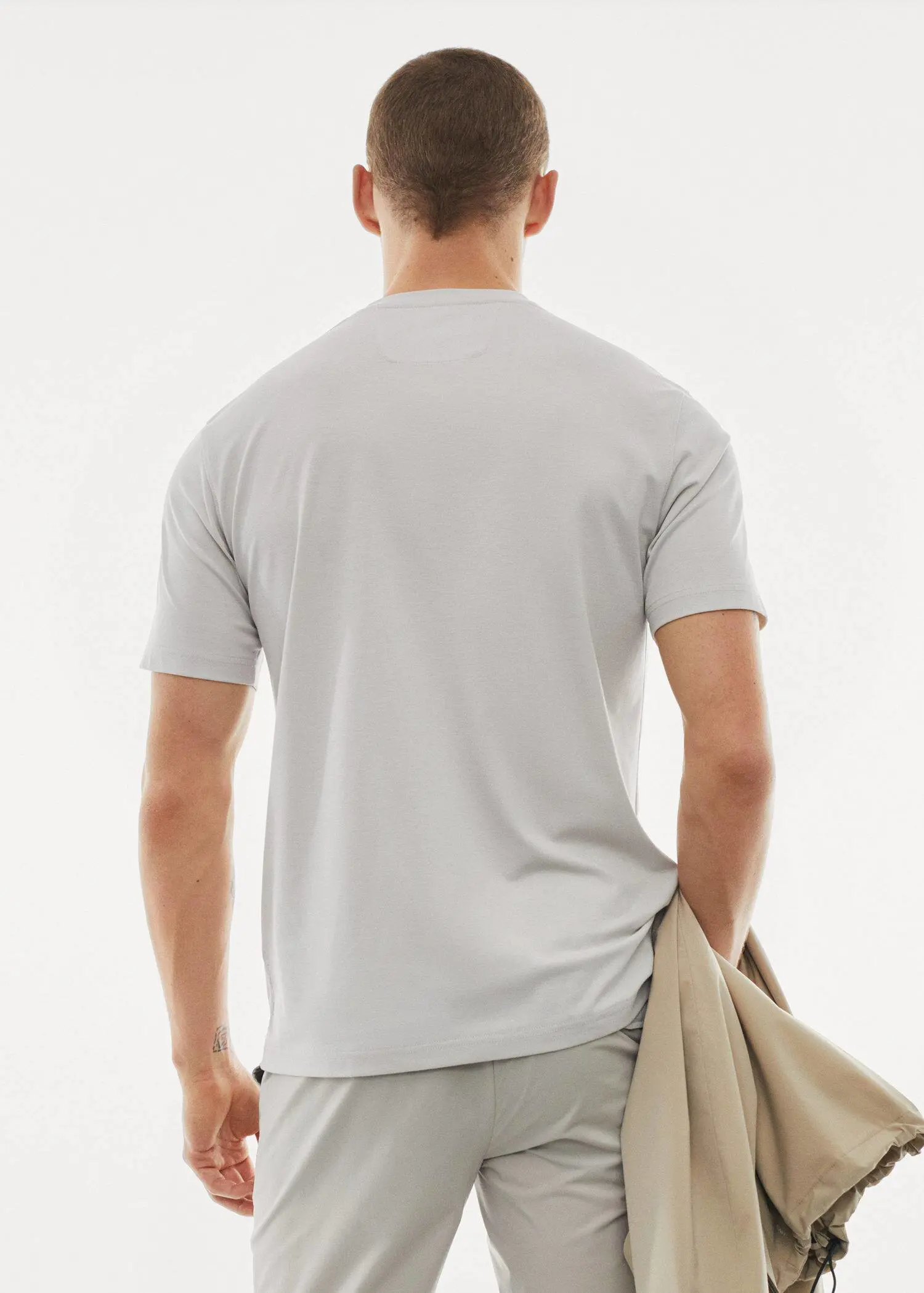 Mango Quick-drying technical t-shirt. a man in a white shirt is holding a jacket. 