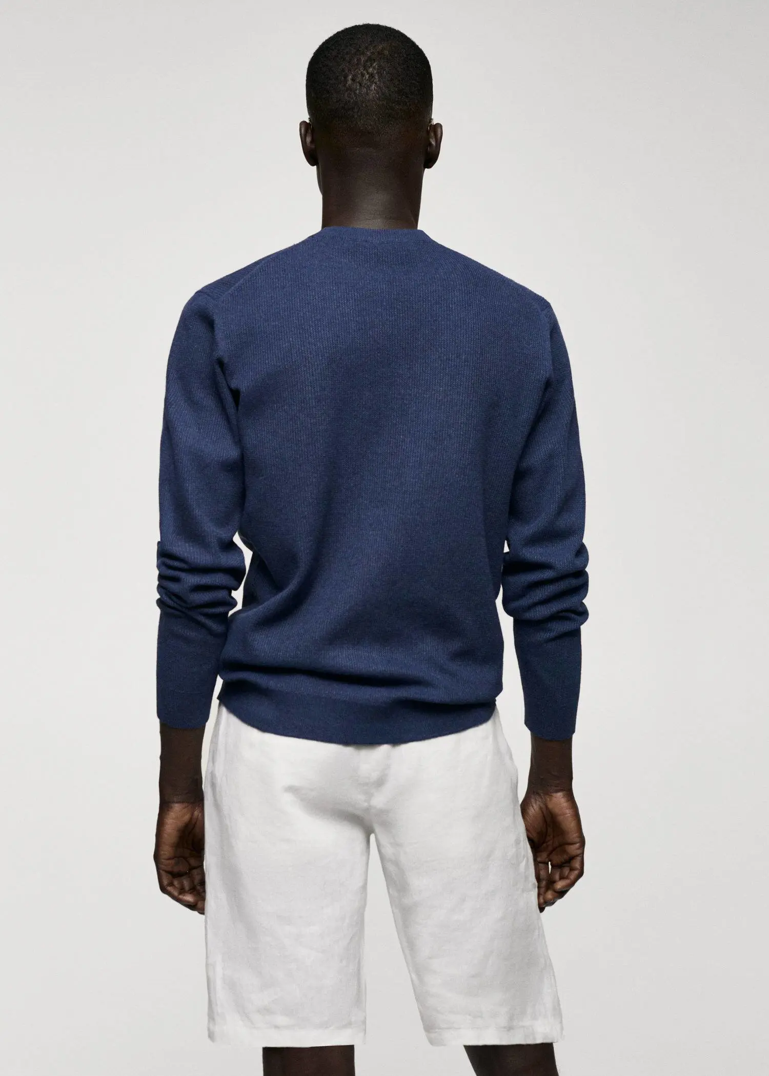 Mango Structured cotton sweater. a man wearing a blue sweater standing in front of a wall. 