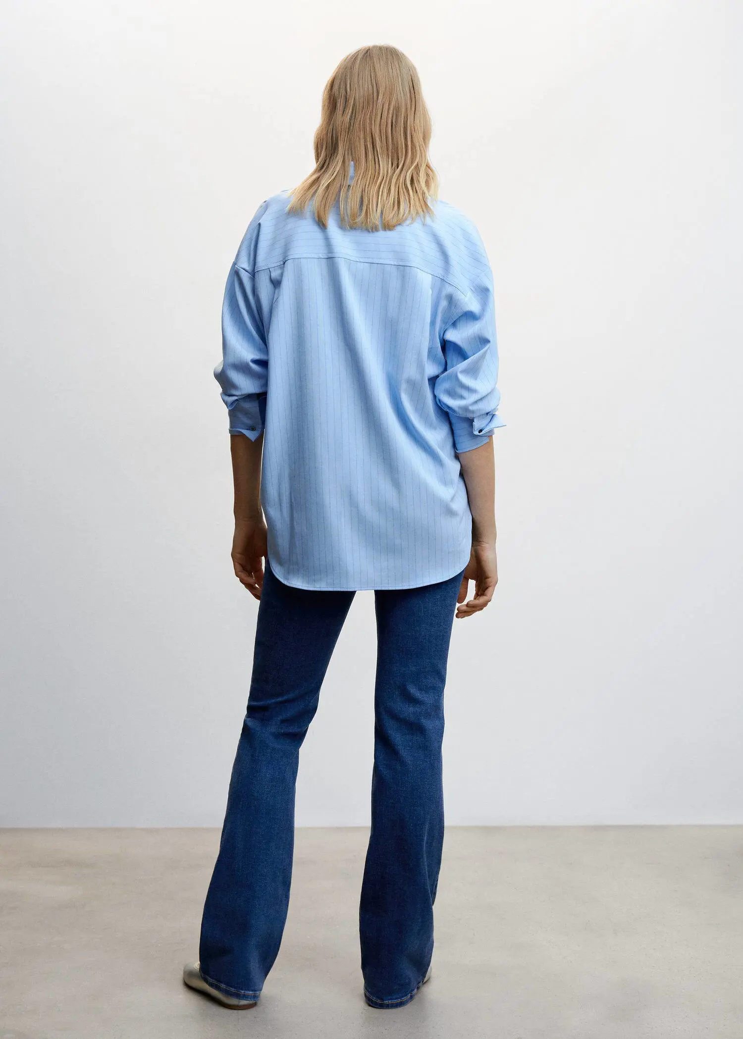 Mango Maternity flared jeans. a person standing in front of a white wall. 